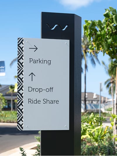 Directional pylon sign with wave icon for parking, drop-off, and ride share at Wai Kai, Ewa Beach, Oahu, wayfinding by RSM Design.