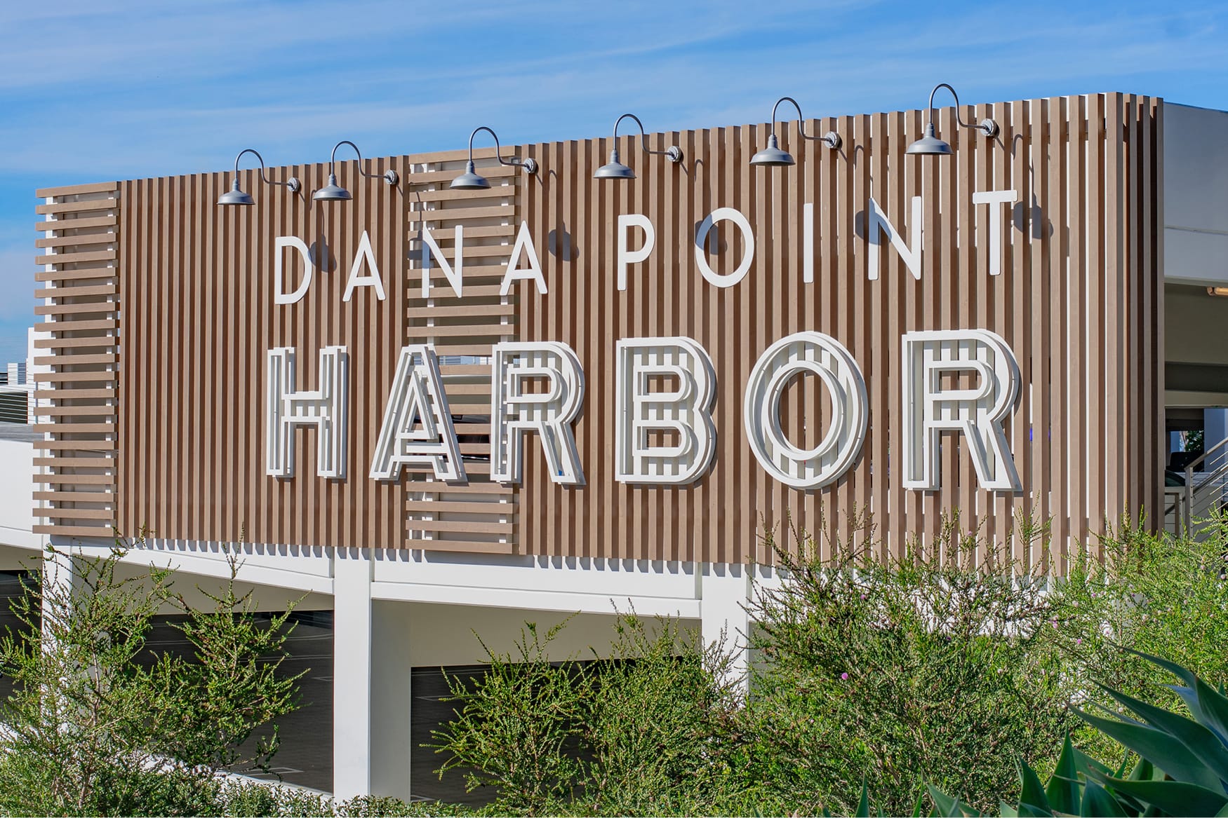 Dana Point Harbor large-scale building identity sign with dimensional lettering on slatted wood facade — environmental graphic design by RSM Design