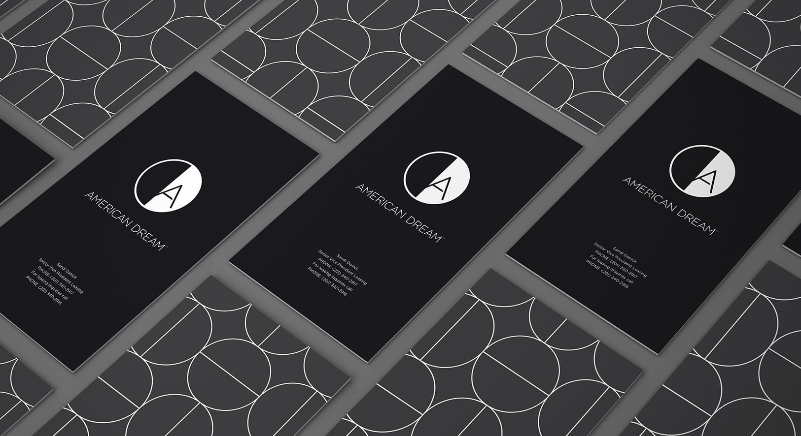 Branded business card suite for American Dream mall in East Rutherford, New Jersey, displaying the American Dream logo mark in white on a matte black card with a geometric brand pattern on the reverse — an example of RSM Design's print and digital collateral and branding and visual identity for a large-scale mixed-use retail and entertainment destination.