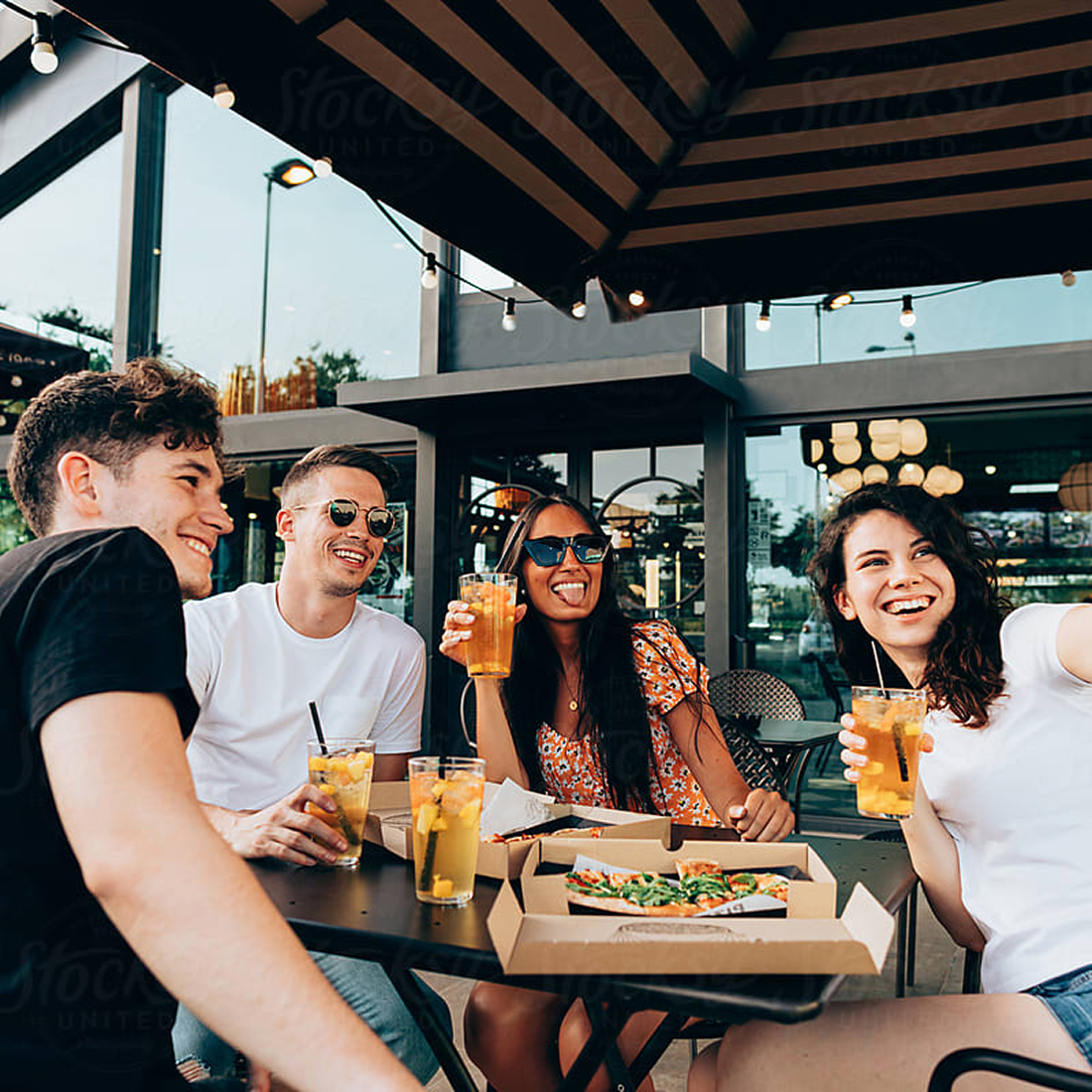 Friends sharing pizza and drinks on an outdoor patio at Uptown Tucson