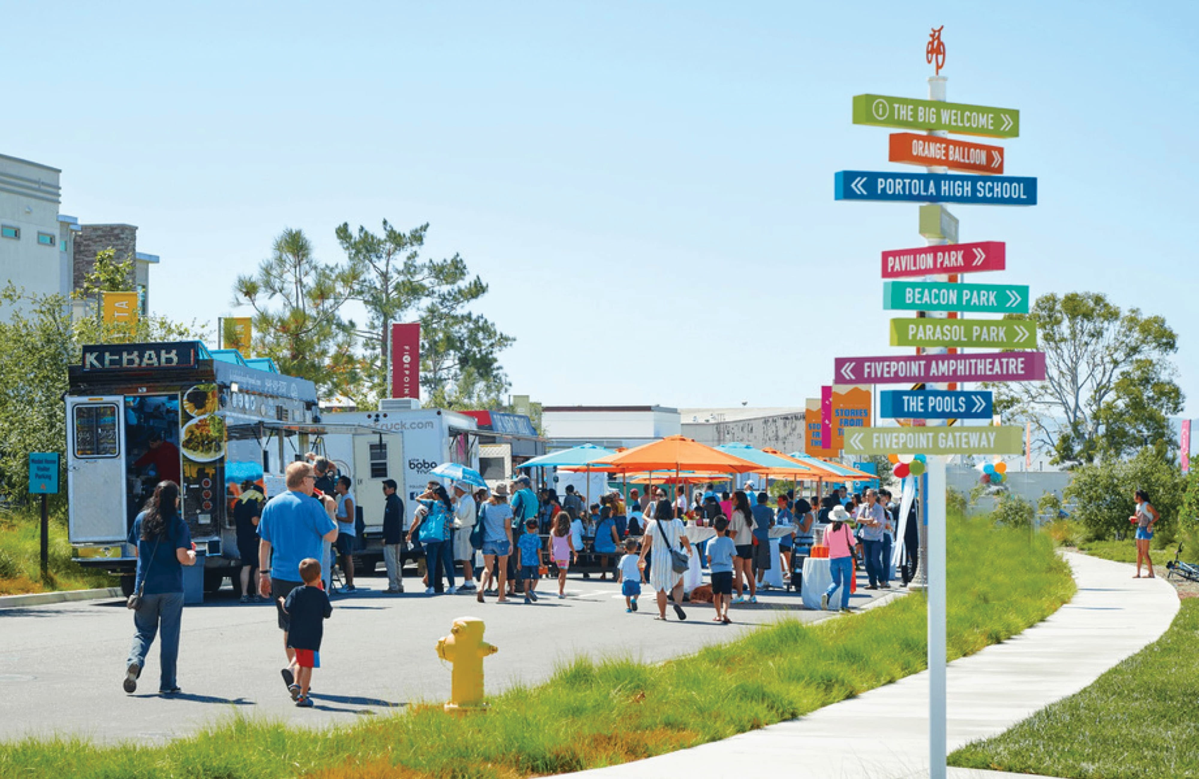 Colorful multi-directional wayfinding signage at a mixed-use community event in Irvine, California, guiding visitors to destinations including Beacon Park and FivePoint Amphitheatre, with placemaking and experiential graphic design by RSM Design.