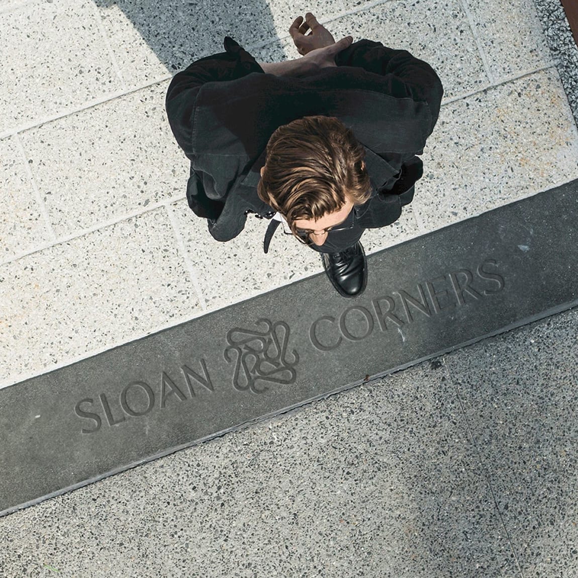 Overhead view of a pedestrian crossing an engraved Sloan Corners paving band - environmental graphic design by RSM Design