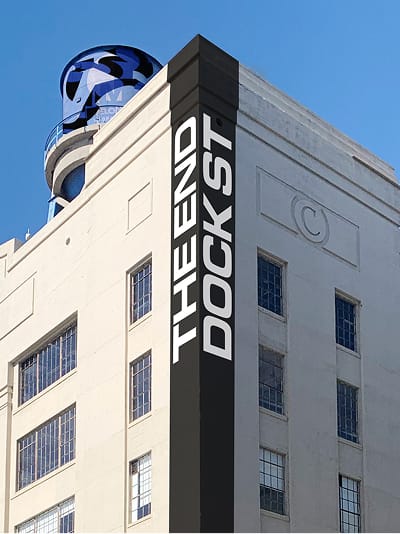 Building corner sign reading "The End, Dock St." on a historic warehouse facade at ROW DTLA - environmental graphic design by RSM Design