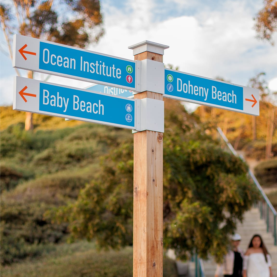 Blue directional street signs pointing to the Ocean Institute, Baby Beach, and Doheny Beach in Dana Point - environmental graphic design by RSM Design