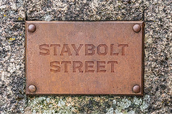 Staybolt Street weathered metal identity plaque with embossed lettering set in stone — environmental graphic design by RSM Design