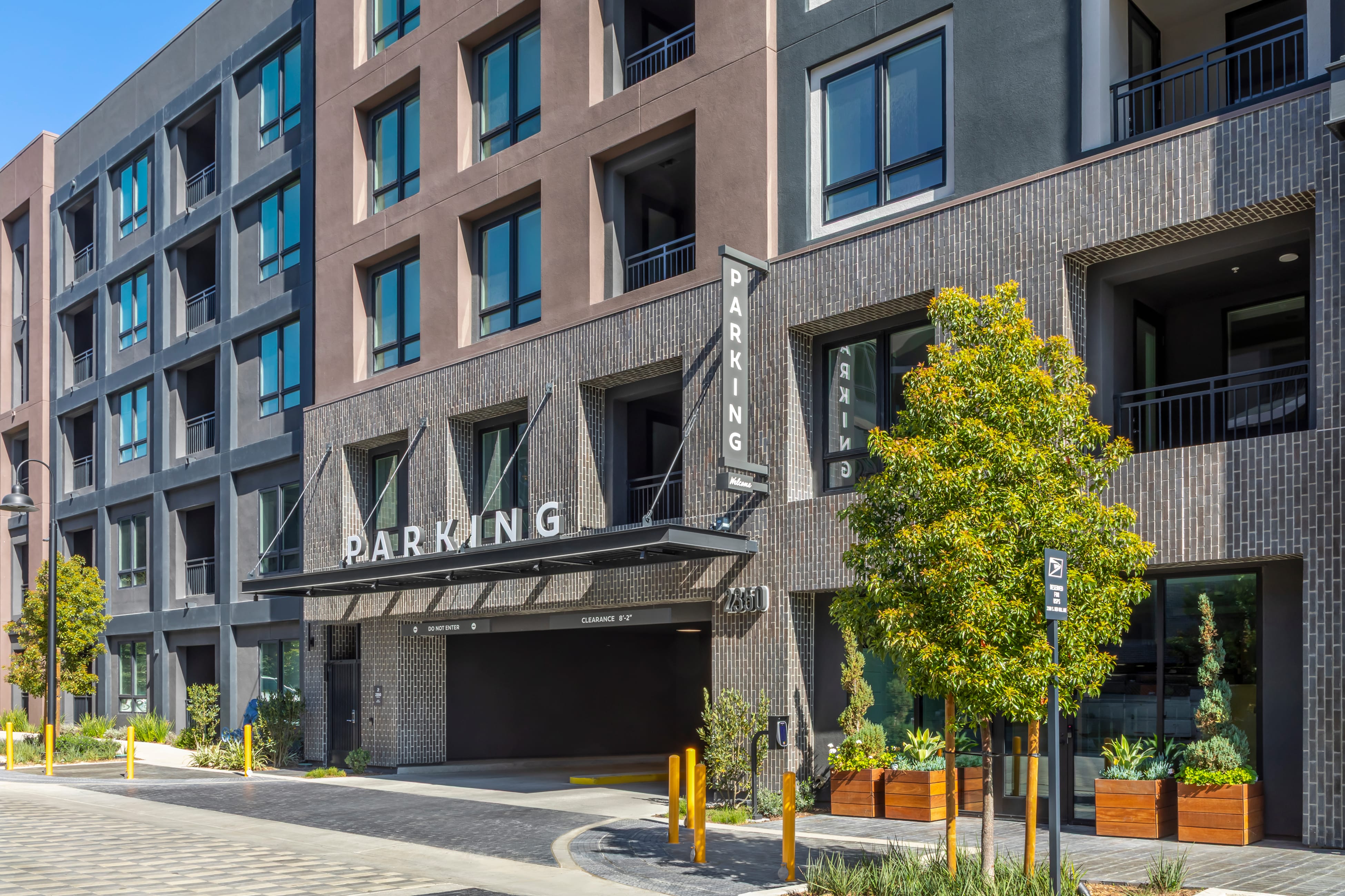 Dimensional "PARKING" sign above a parking garage entrance and blade sign on brick-patterned facade with address numerals "2350" at The Row at Red Hill – placemaking and environmental graphic design by RSM Design.