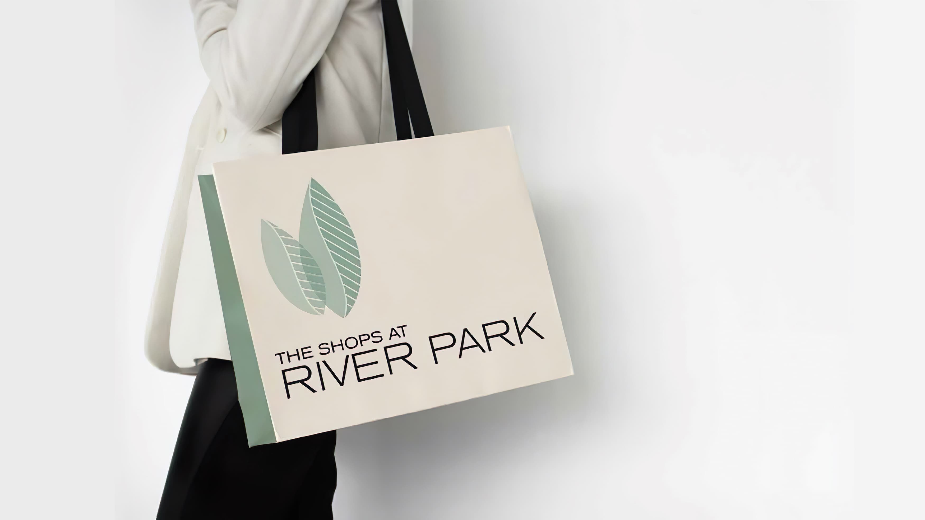 Woman holding a shopping bag branded with the Shops at River Park logo