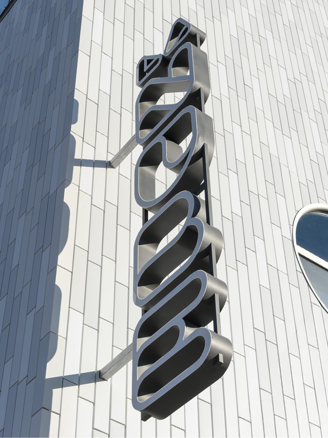 La Nube children's museum vertical dimensional sign detail with sculptural letterforms on tile facade — environmental graphic design by RSM Design
