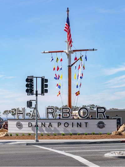 Dana Point Harbor gateway monument with dimensional lettering and nautical mast landmark at harbor entrance — environmental graphic design by RSM Design