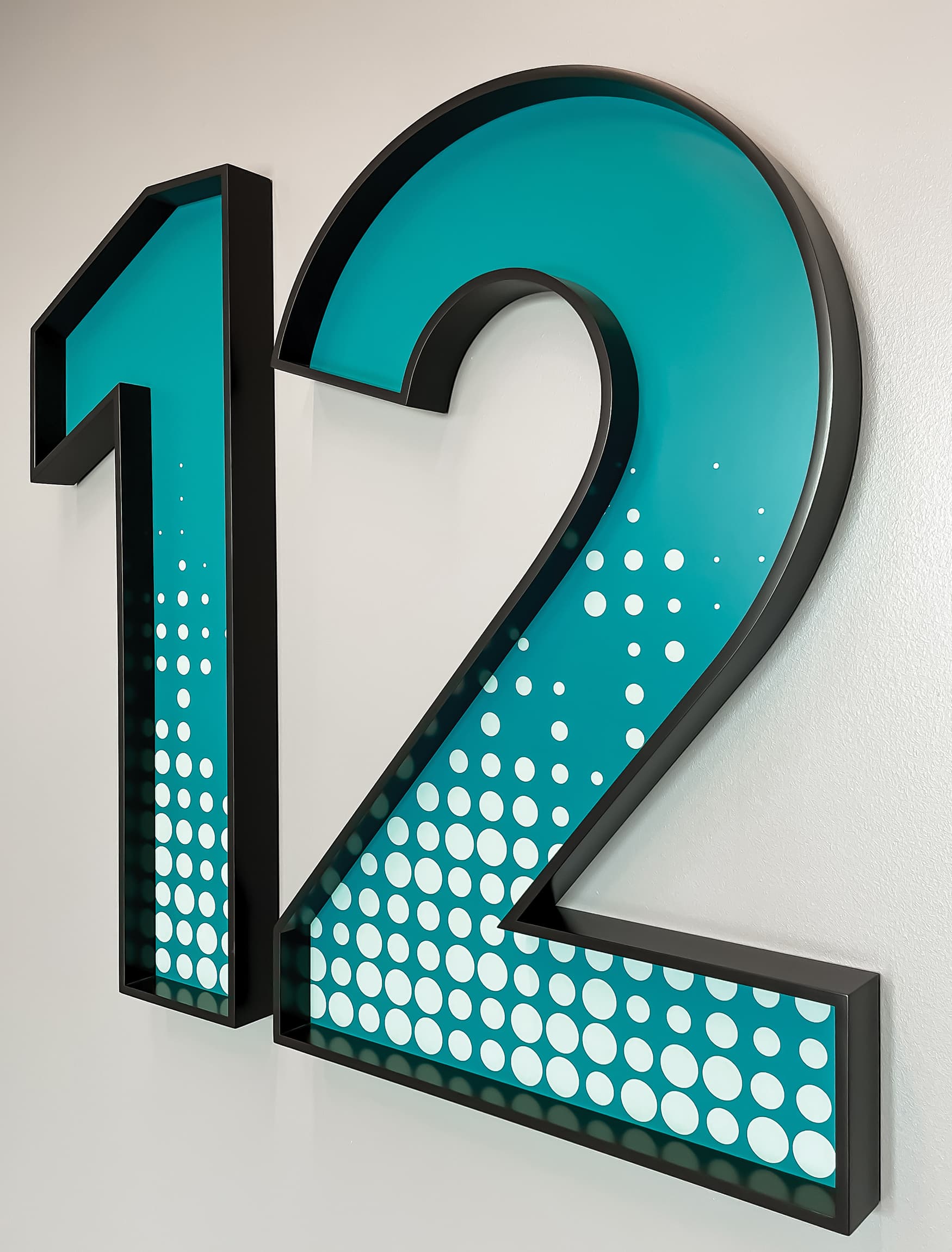 Large number signage for Chemonics International by RSM Design. Blue number "12" with white circle and black outlined signage. 