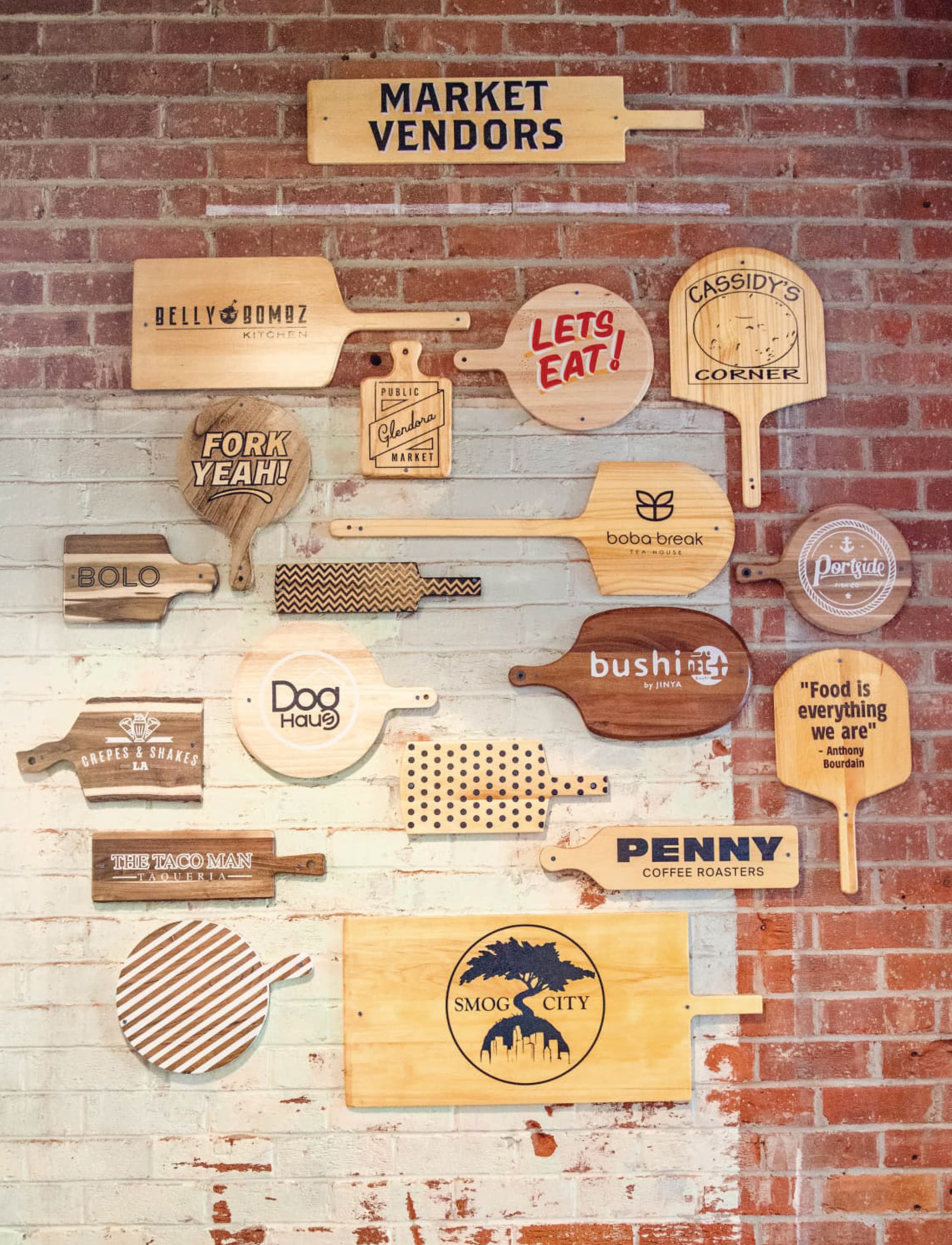 Custom environmental graphic design feature wall showcasing market vendor identities on wood paddles, integrating brand strategy, placemaking, and signage design for a public market retail and hospitality destination by RSM Design