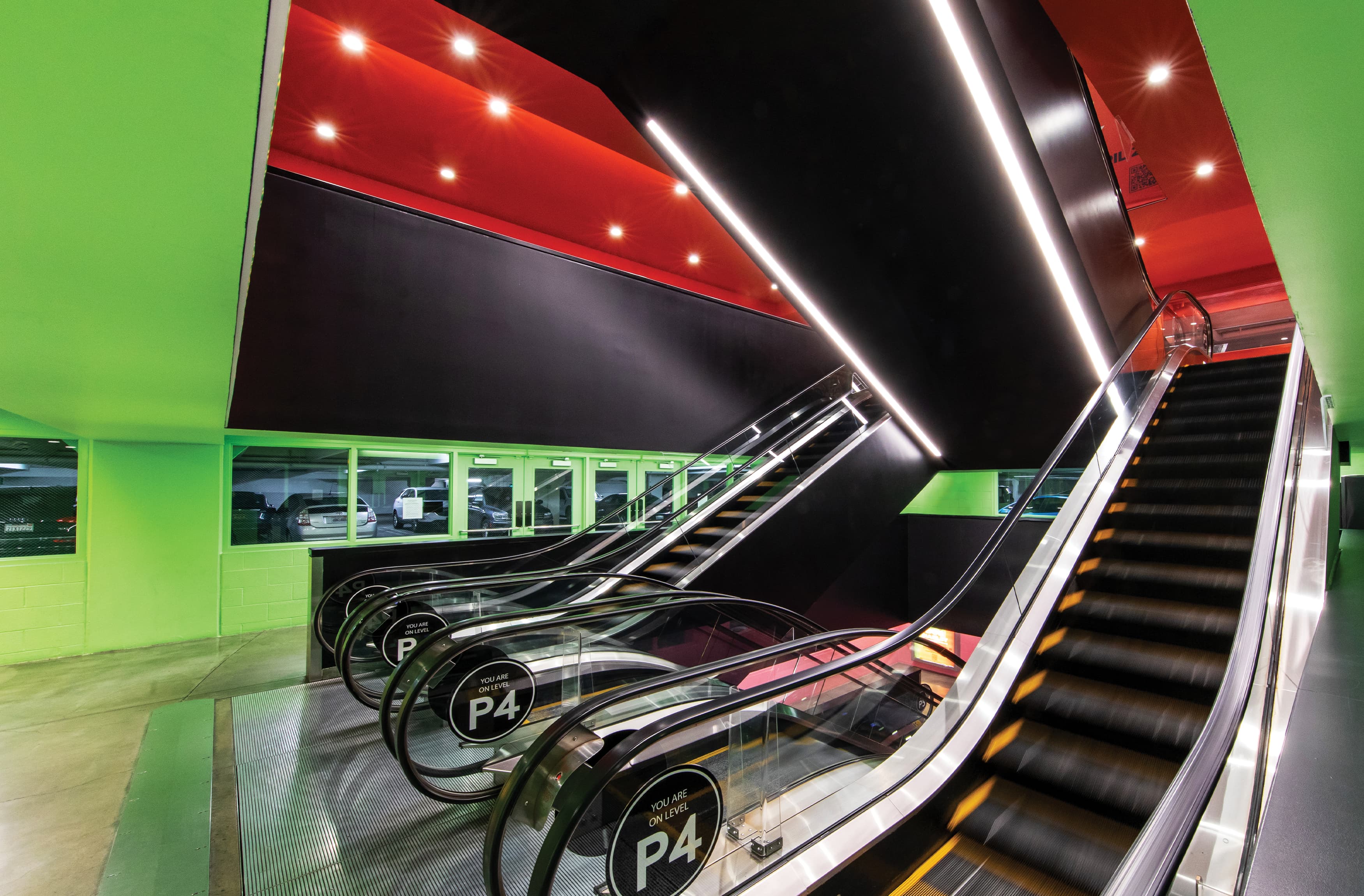 Parking garage escalator level identity in black with white graphics applied to escalator glass by RSM Design for Ovation Hollywood in Los Angeles, California