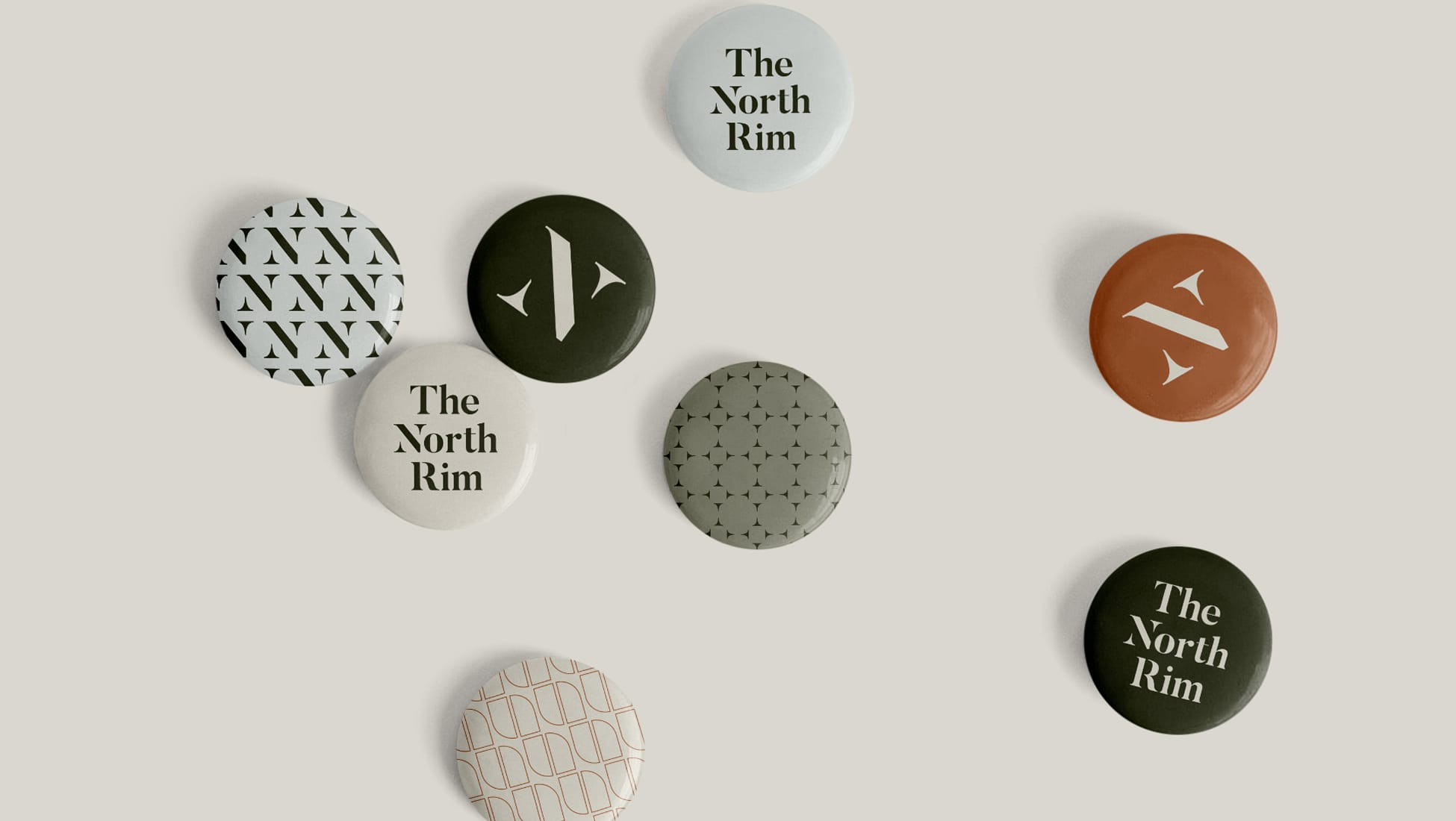 The North Rim brand identity pinback button collection in olive, terracotta, and cream, featuring logo mark, wordmark, and geometric patterns, brand identity design by RSM Design