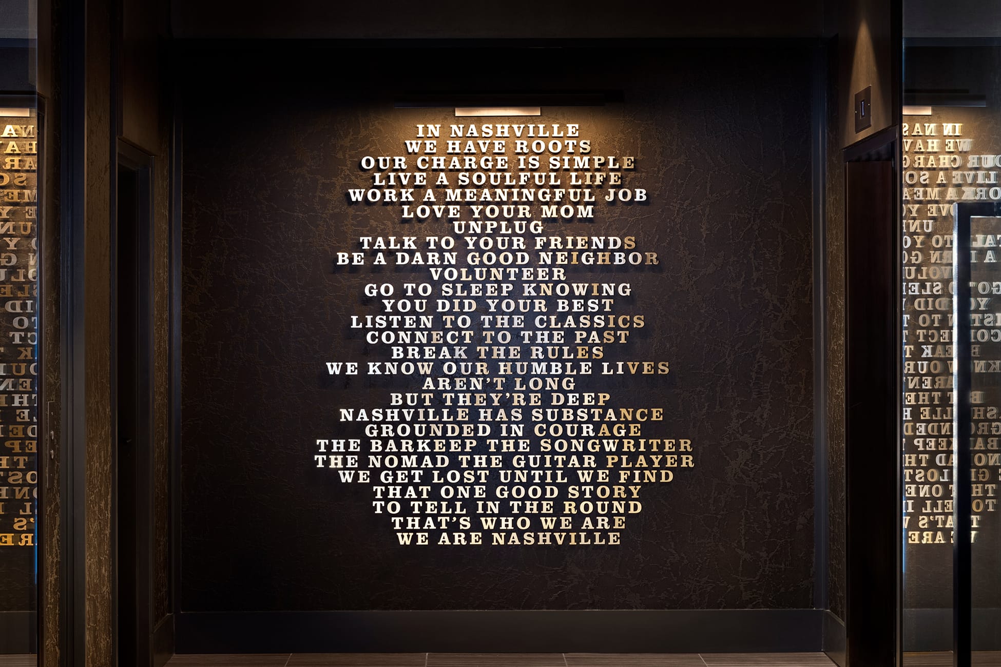 Feature wall at Fifth + Broadway with illuminated typographic installation expressing Nashville’s culture and values within a refined interior setting.