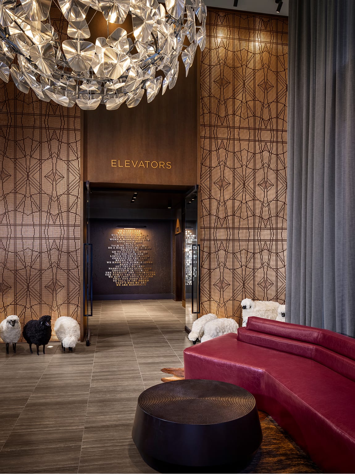 Residential lobby at Fifth + Broadway featuring elevator wayfinding signage integrated into a warm, material-rich interior with layered textures and custom lighting.