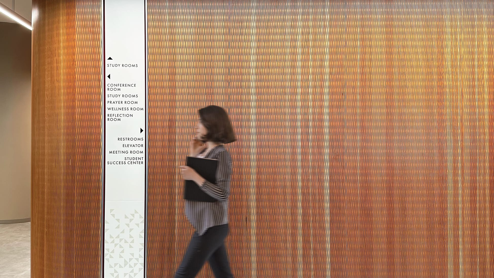 RSM Design developed the environmental graphics and wayfinding system for the Campus Center at Rinker, Chapman University's Irvine campus. The interior signage program guides students across a range of campus facilities — including study rooms, wellness and reflection rooms, conference spaces, and the Student Success Center — while integrating seamlessly with the building's warm material palette of textured wood-tone feature walls. The design balances clear wayfinding functionality with a human-scaled, welcoming academic environment, reinforcing Chapman University Irvine's commitment to student wellbeing and campus community through intentional environmental graphic design.