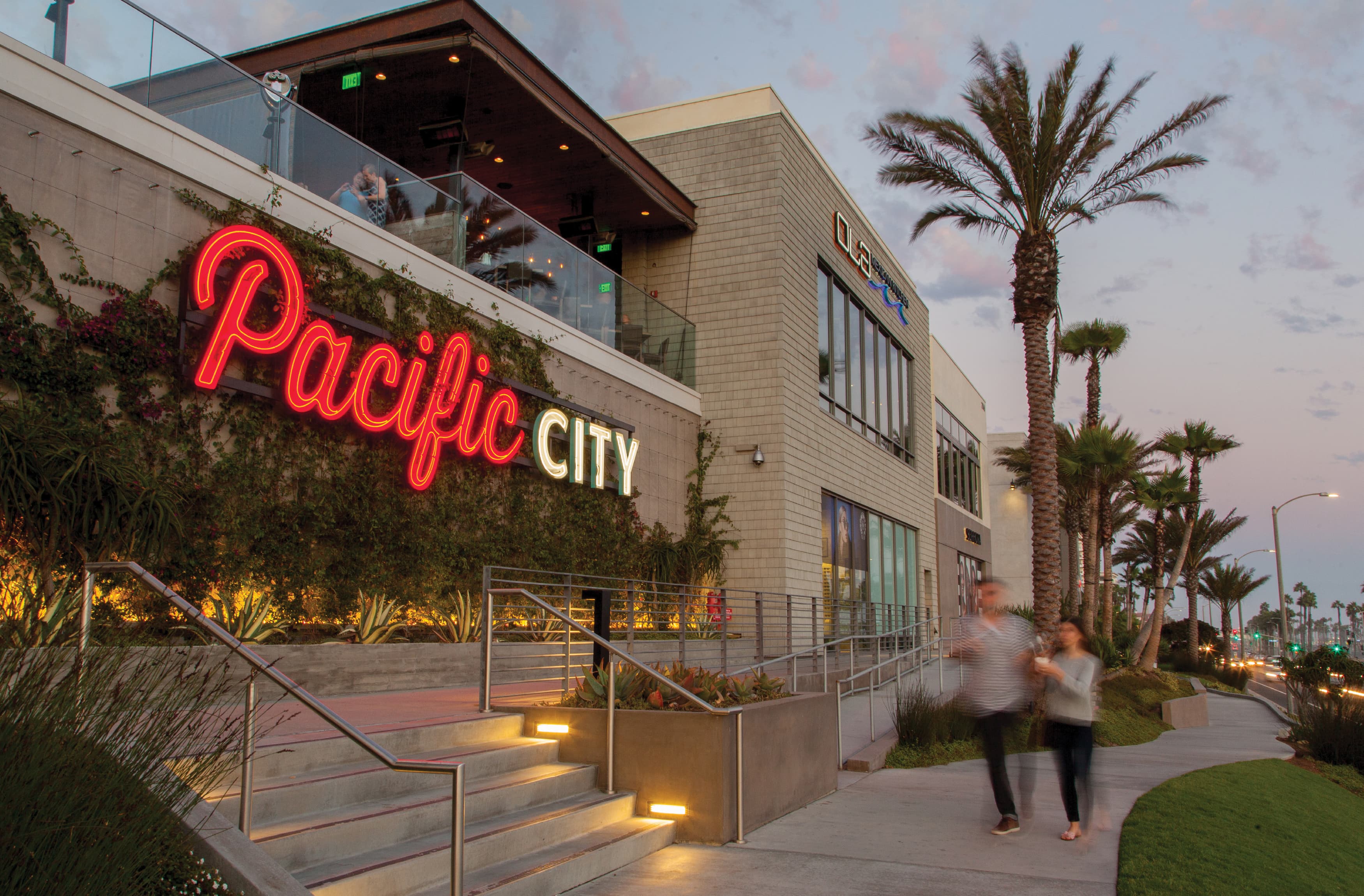 Image of two people walking down the street in front of Pacific City, in Huntington Beach, CA. Master sign designed by RSM Design. 