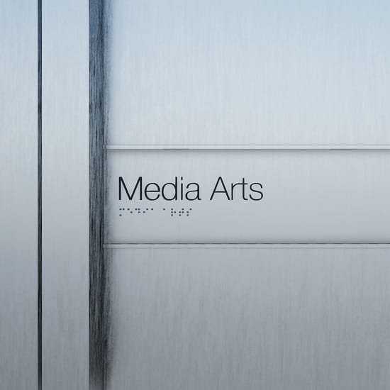 Close-up of ADA-compliant Media Arts room identification sign with Braille text on brushed aluminum panel at University of Arkansas Windgate Arts and Design District