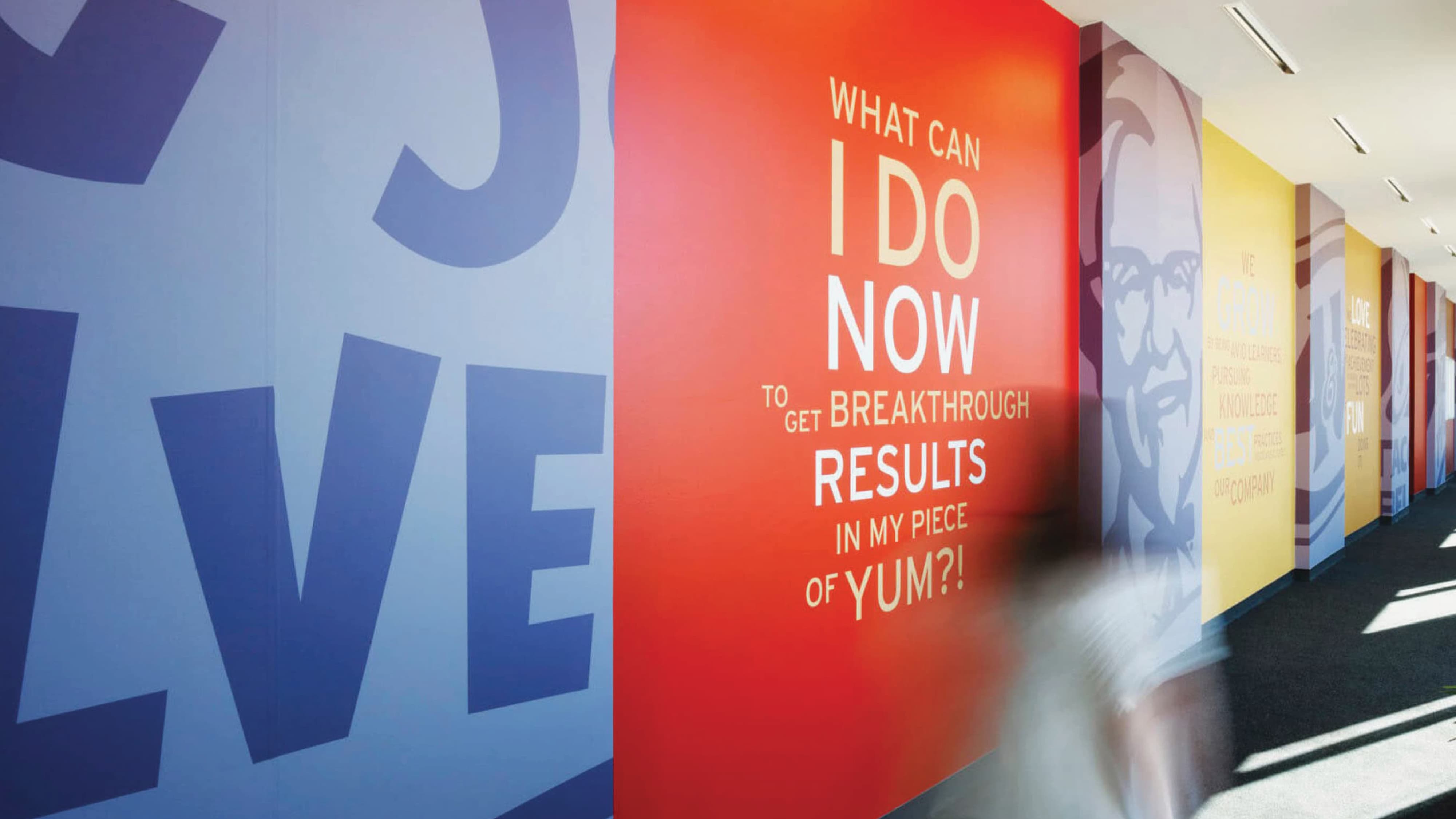 Interior branded environment featuring large-scale environmental graphic design and graphic wall installations that communicate brand messaging and storytelling within a corporate workplace environment.