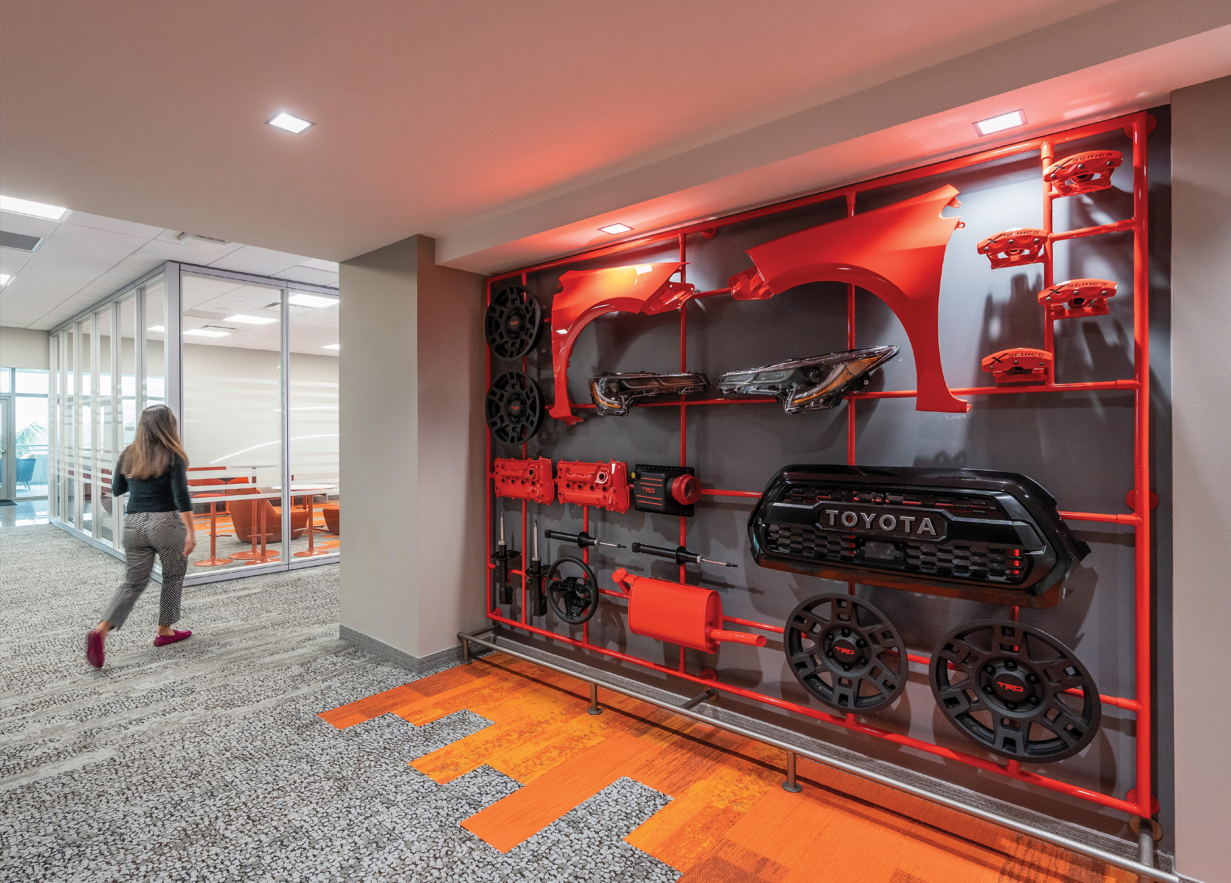 Automotive-themed environmental graphic design installation featuring branded vehicle components integrated into a workplace interior, showcasing experiential design, brand storytelling, and placemaking for corporate, mobility, and innovation-driven environments.