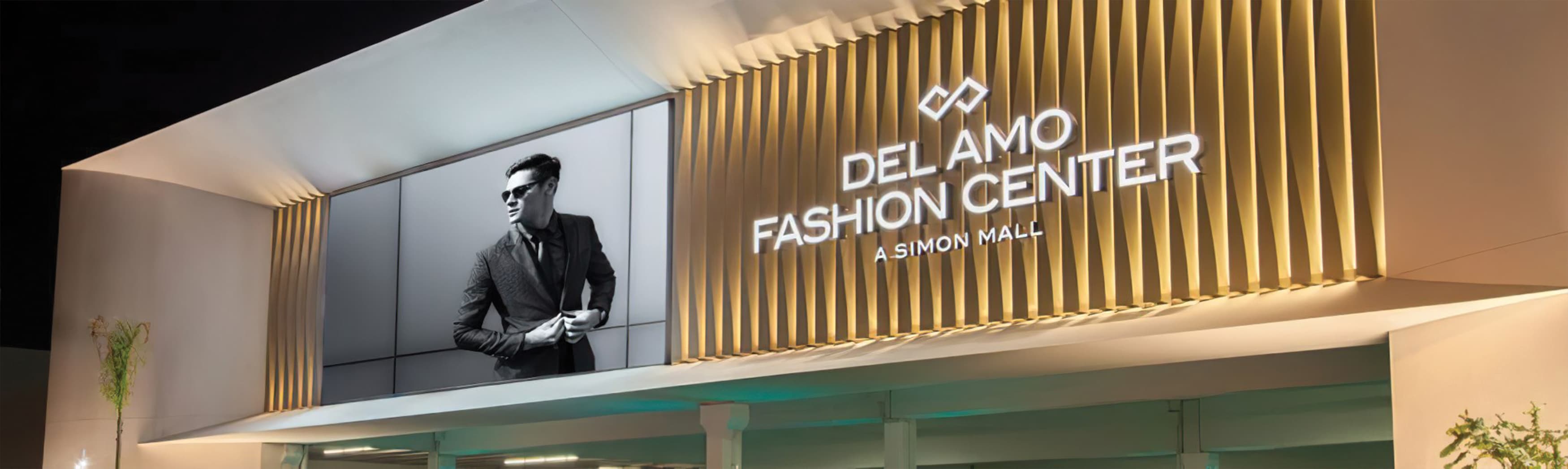 A nighttime image featuring an illuminated channel letter sign and a lifestyle graphic, both mounted on an architectural facade at Del Amo Fashion Center.