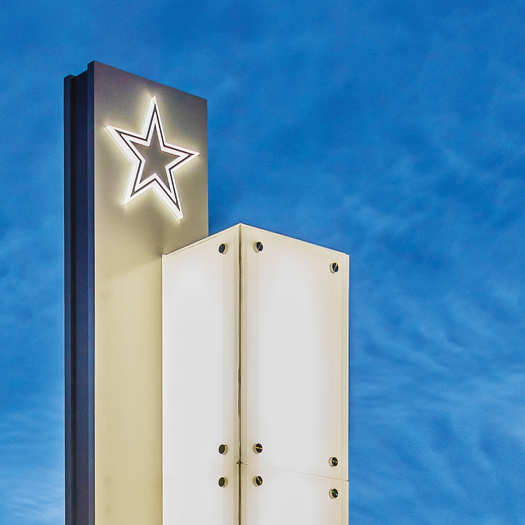Dallas Cowboys logo illuminated pylon signage at dusk