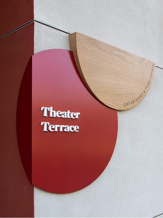Sculptural red and wood Theater Terrace donor sign with layered circular forms at Brentwood School campus in Los Angeles - environmental graphic design by RSM Design