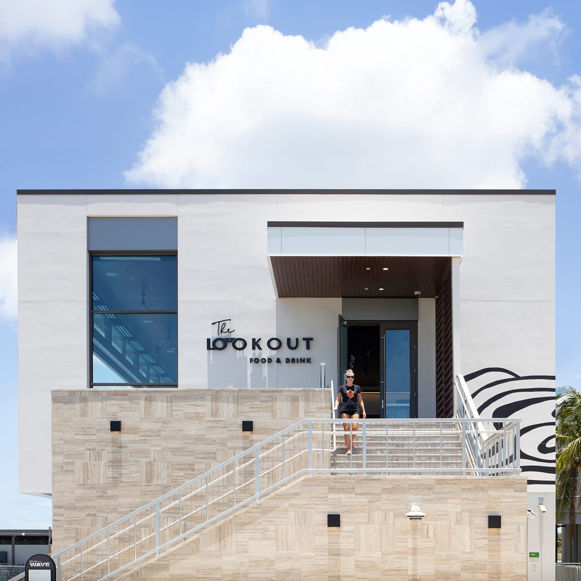 The Lookout Food and Drink building exterior with travertine stairway and graphic wave mural at Wai Kai, Ewa Beach, Oahu, environmental graphic design by RSM Design.