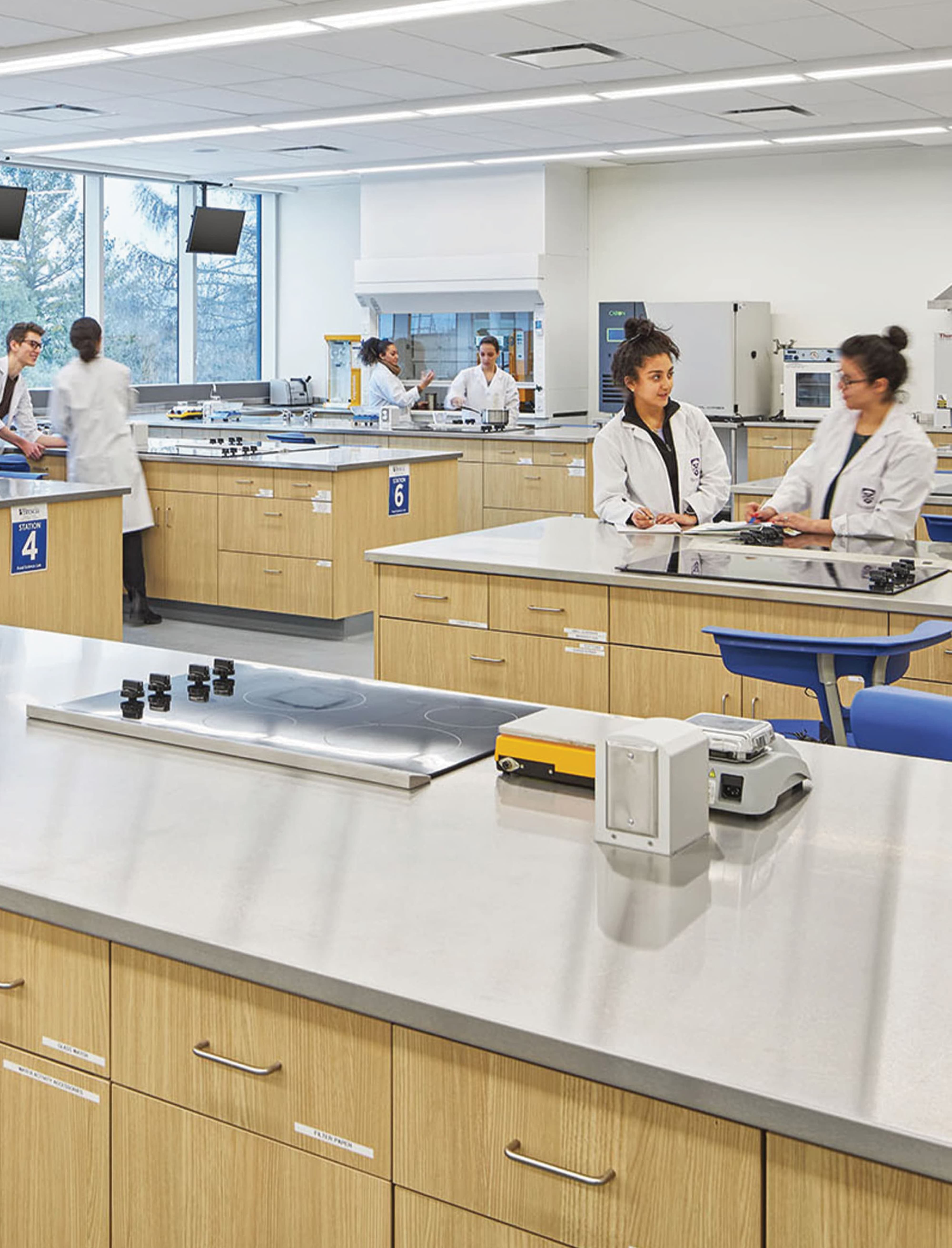 Students working in a modern science laboratory classroom, illustrating educational environments where environmental graphic design, wayfinding, and placemaking support learning, research, and campus experience design.