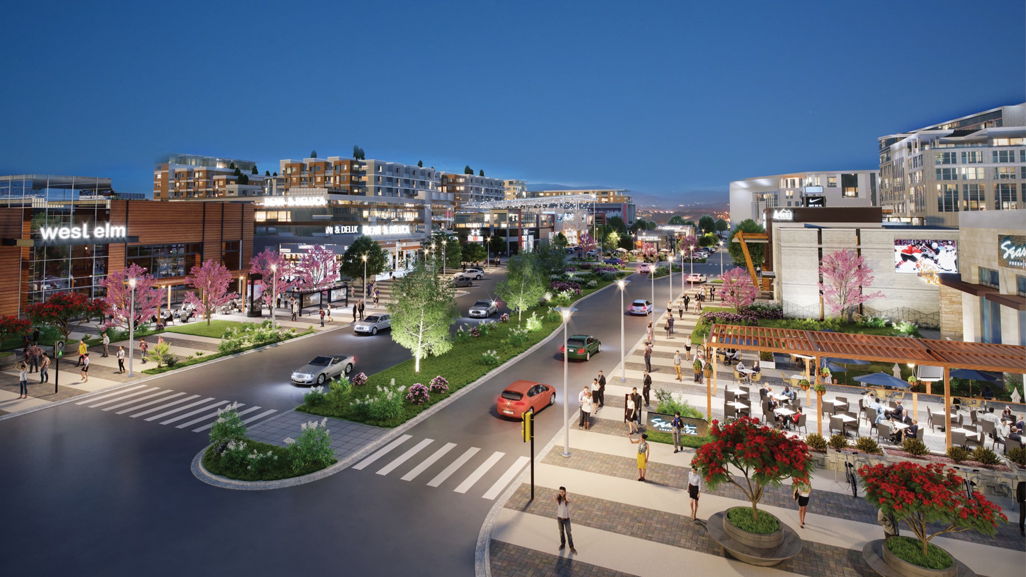 Evening view of a mixed-use and retail development with shopping, dining, and people walking around outdoors.