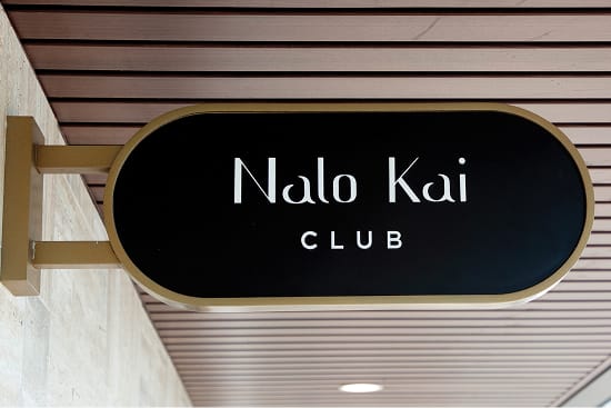 Nalo Kai Club oval blade sign in black and brass mounted beneath wood ceiling at Wai Kai, Ewa Beach, Oahu, environmental graphic design by RSM Design.