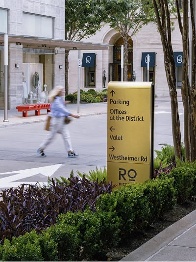 River Oaks District Houston gold directional sign for parking and valet near retail storefronts, wayfinding design by RSM Design