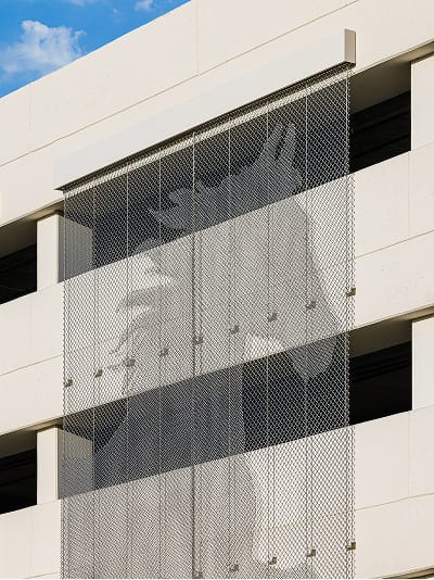Close-up detail of large-scale figural graphic printed on perforated metal screen panels on a parking garage exterior facade — RSM Design specialty graphics, experiential graphics, branded environments, and placemaking where architecture and environmental graphic design intersect for parking garage and mixed-use destinations.