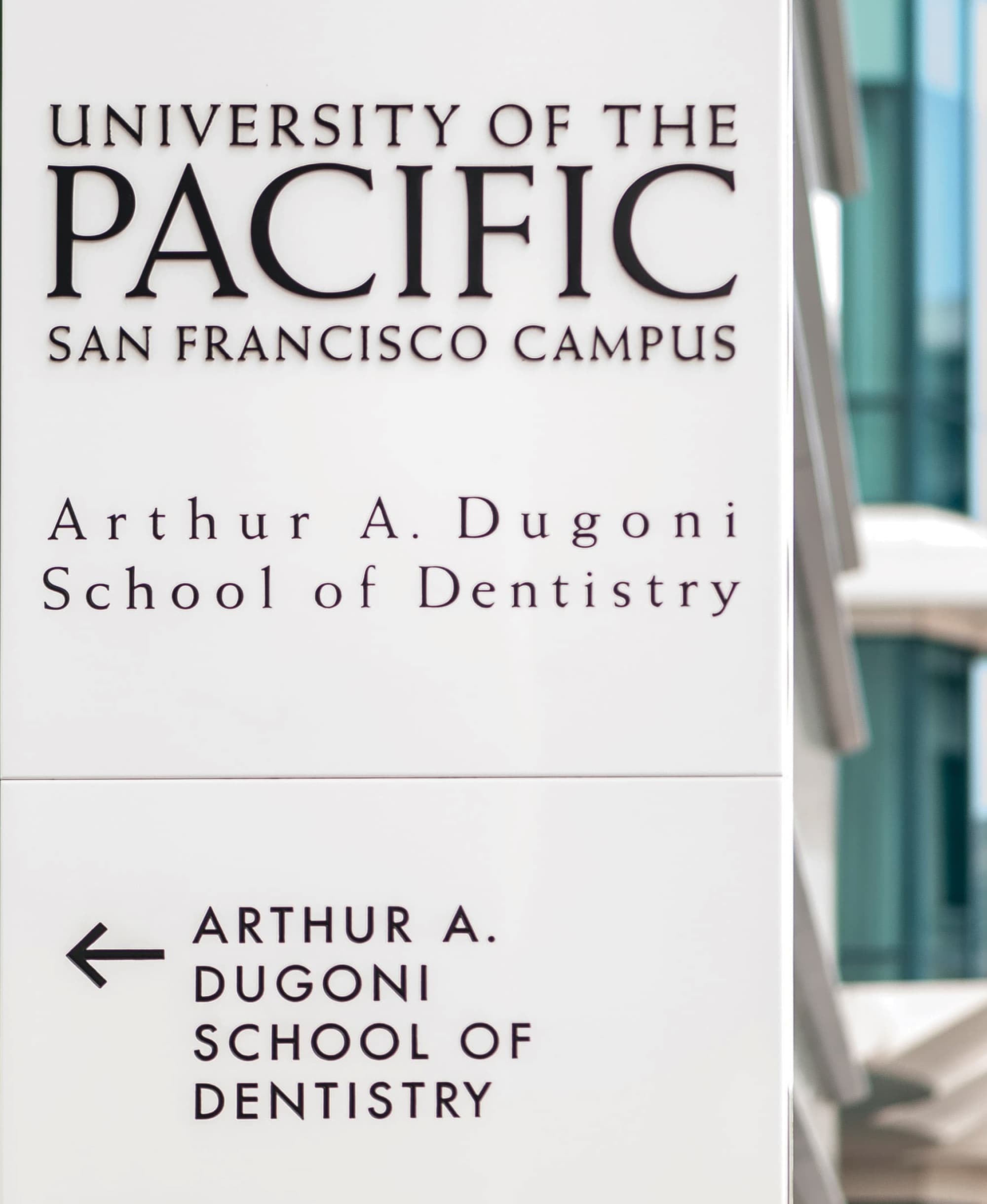 Close-up detail of a University of the Pacific San Francisco Campus exterior wayfinding pylon sign with dimensional institutional logotype and directional arrow to Arthur A. Dugoni School of Dentistry — RSM Design wayfinding and signage design, master sign programs, branding and visual identity, and environmental graphic design for education and health and wellness destinations.