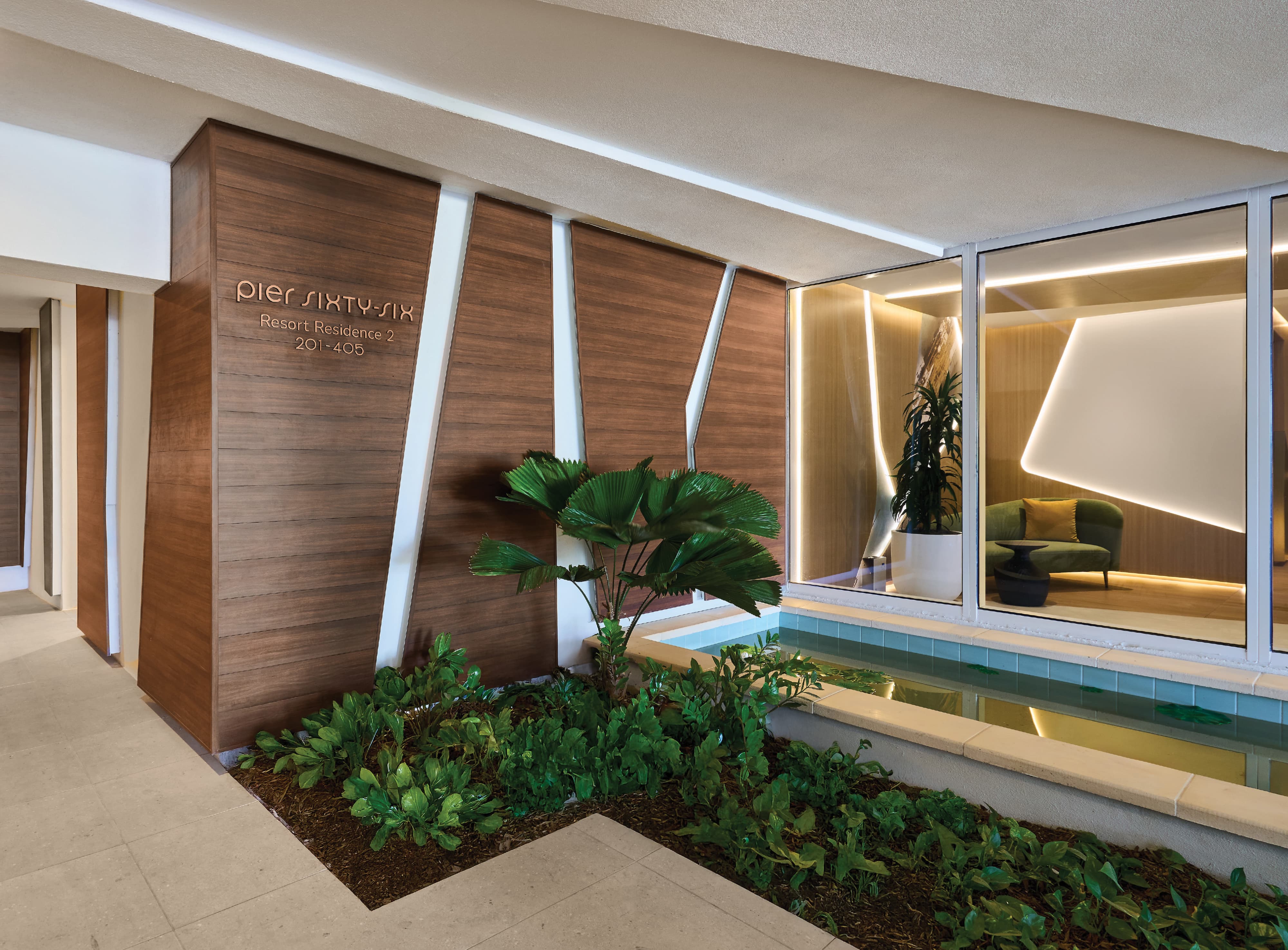 Pier Sixty-Six Resort Residence 2 building identification and unit directory signage mounted on a warm wood veneer entry wall with tropical landscaping and reflective pool at Pier Sixty-Six luxury waterfront resort in Fort Lauderdale, Florida — RSM Design wayfinding and signage design, master sign programs, branded environments, and environmental graphic design for hospitality, waterfront, and residential community destinations.