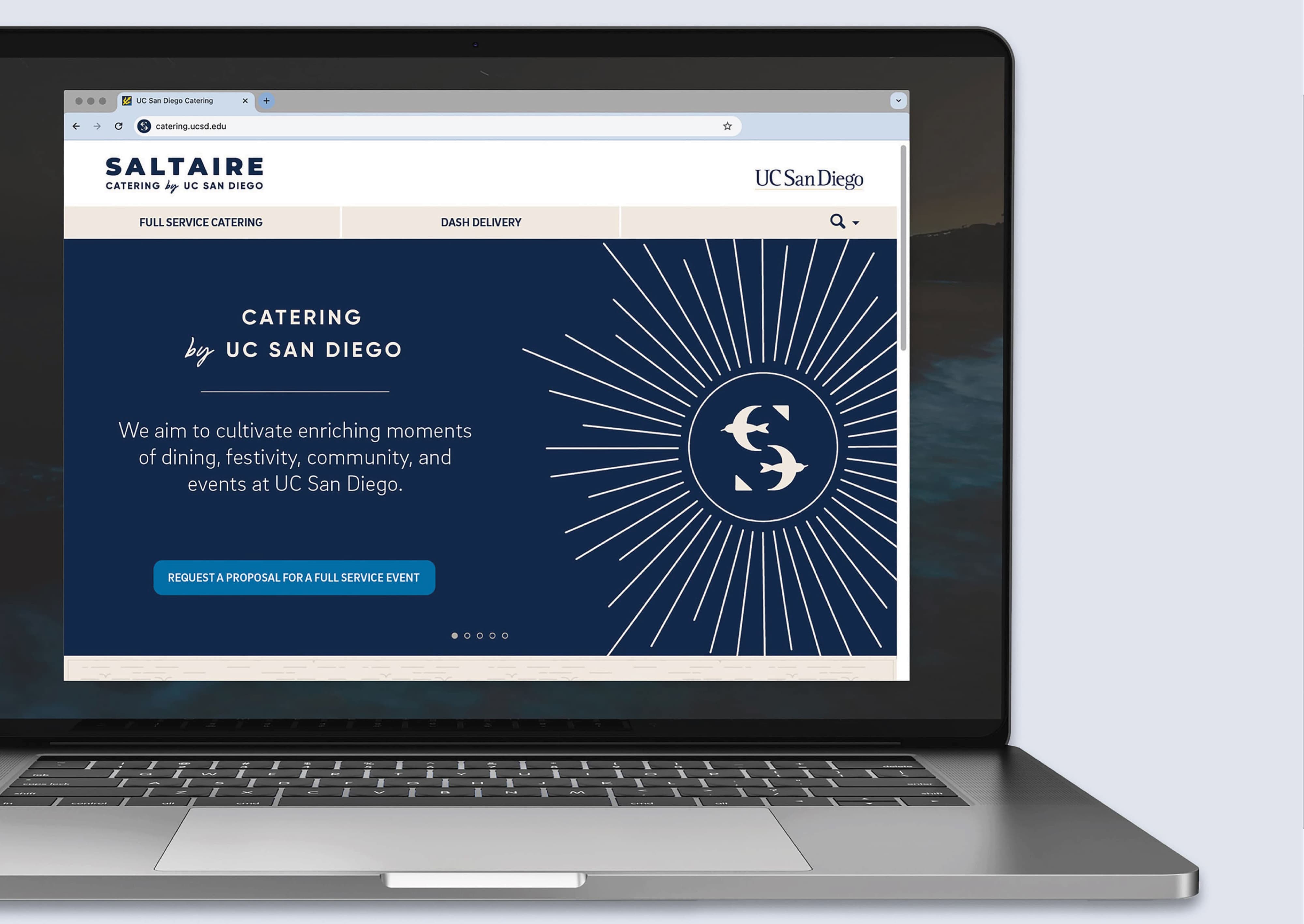 Laptop displaying the Saltaire Catering by UC San Diego website homepage featuring the sunburst tern lettermark on a navy background, showcasing digital collateral and visual identity design for a food and beverage and education market client by RSM Design.