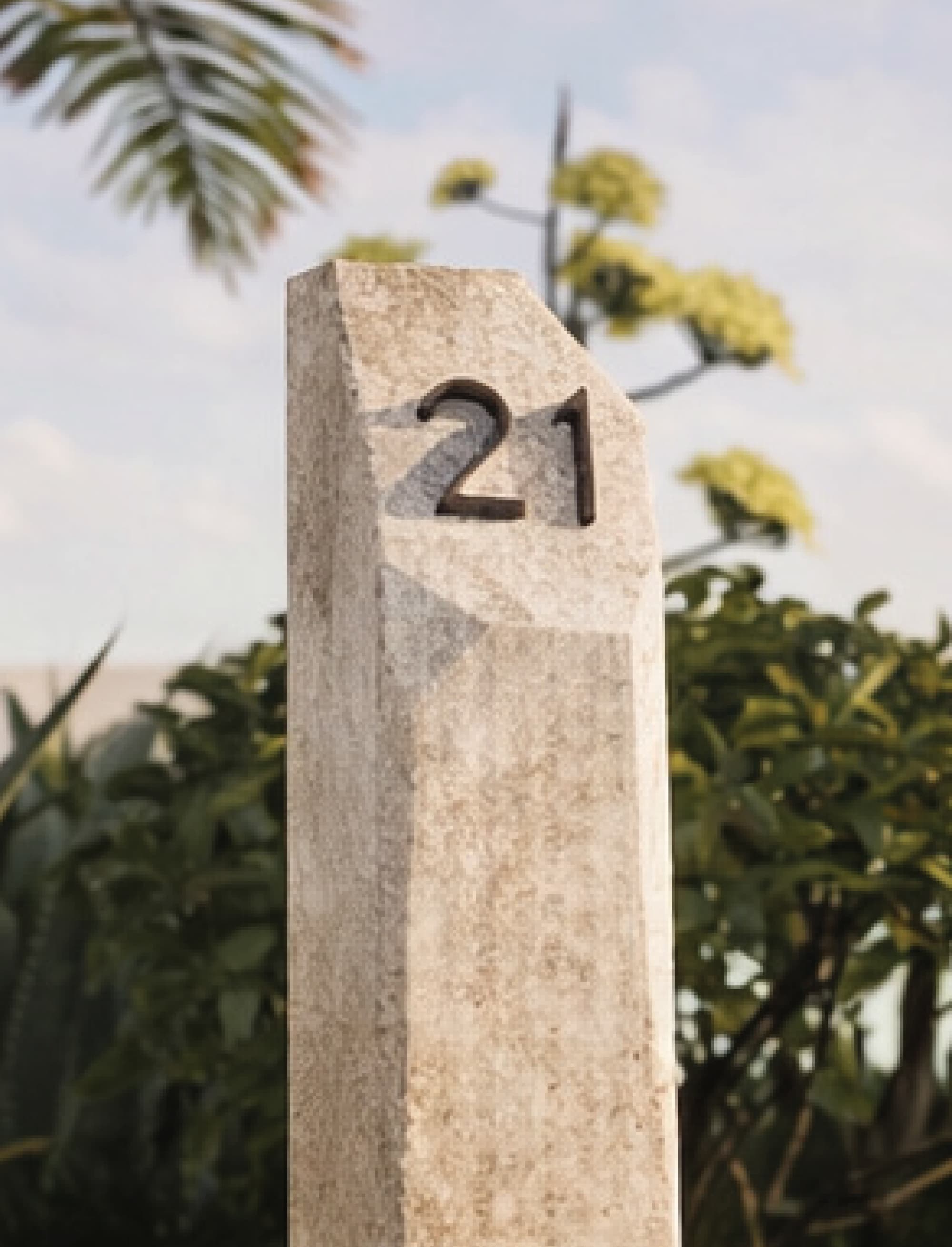Stone monument wayfinding marker with carved unit number “21” integrated into landscape, showcasing environmental graphic design, placemaking, and experiential wayfinding for residential, mixed-use, and hospitality environments.