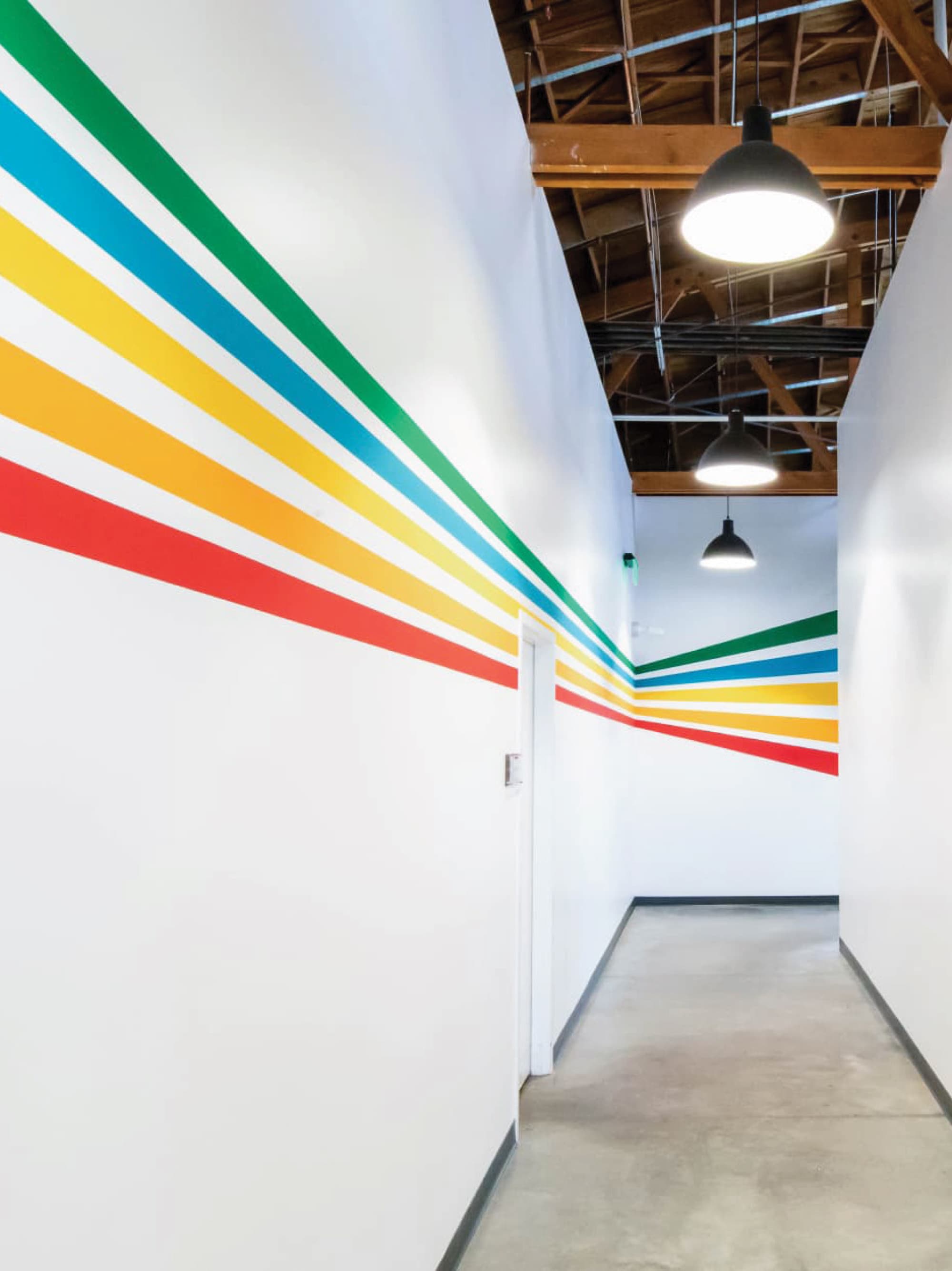 Interior corridor with colorful environmental graphics and linear wall wayfinding, integrating brand identity, placemaking, and signage design to enhance navigation and user experience within a mixed-use retail and hospitality environment by RSM Design