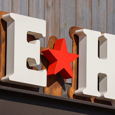 Detail shot of Ice House dimensional channel letter signage featuring white fabricated letters, red star accent, and corten steel backer on wood siding at PGA Frisco