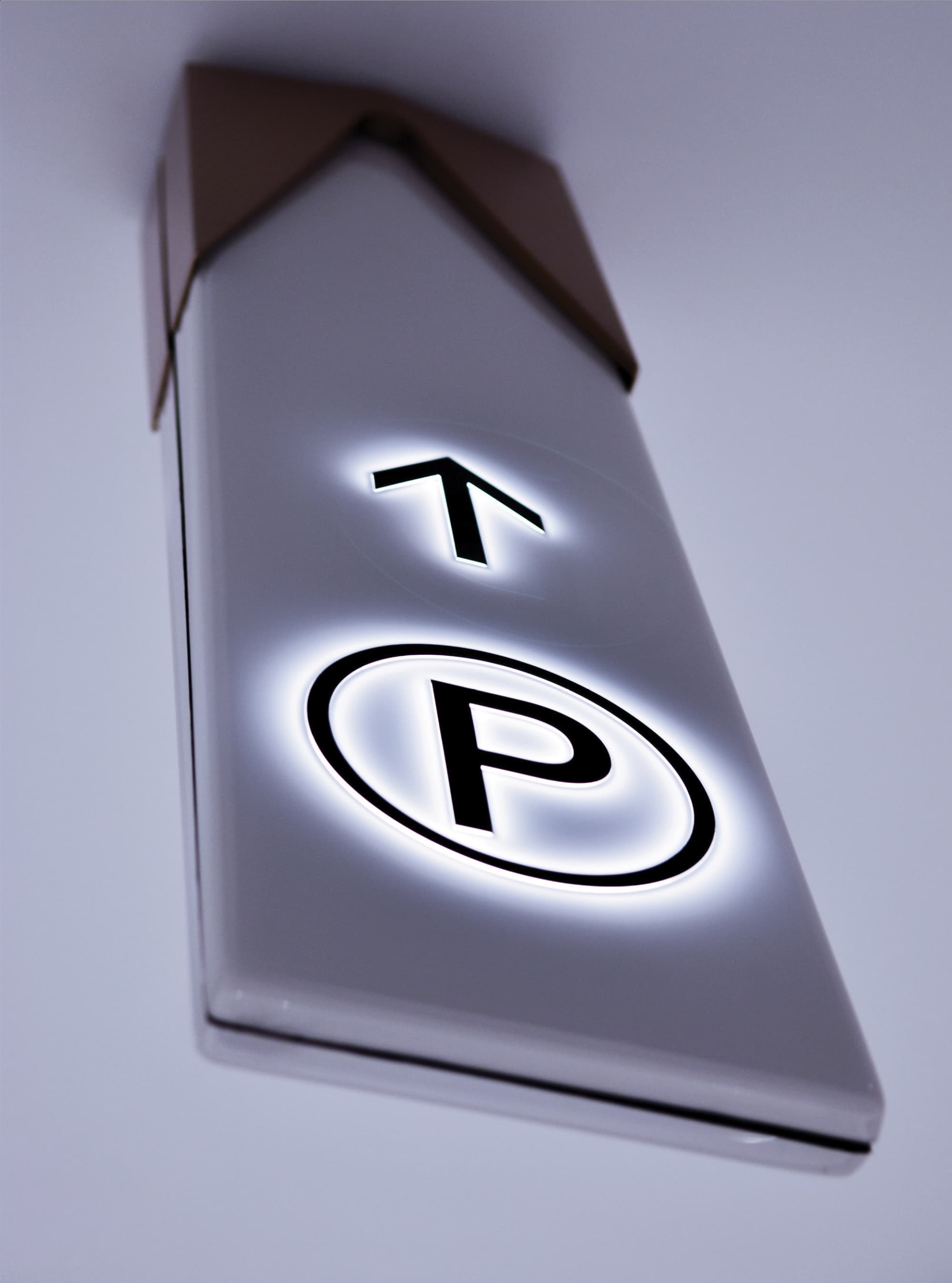 Illuminated parking wayfinding sign with directional arrow and “P” symbol, illustrating environmental graphic design, signage systems, and intuitive navigation for retail, mixed-use, and commercial parking environments.