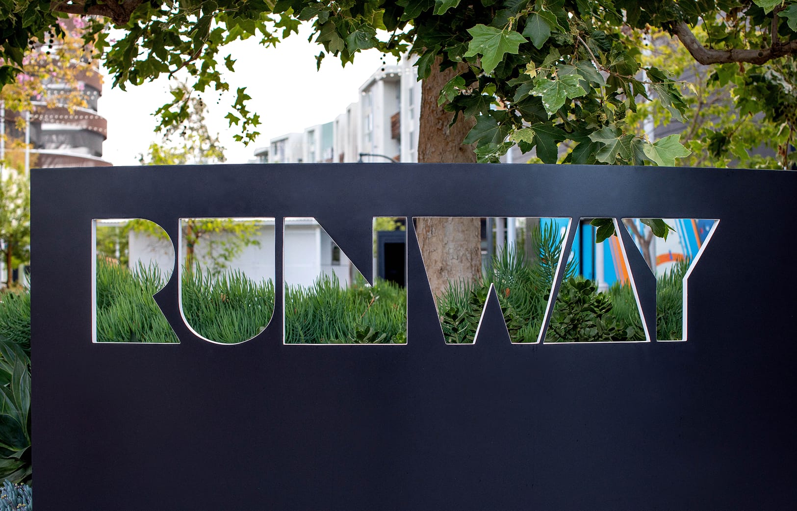 Runway Playa Vista monument signage with cut-out lettering integrated into landscaped pedestrian environment, showcasing environmental graphic design and placemaking by RSM Design.