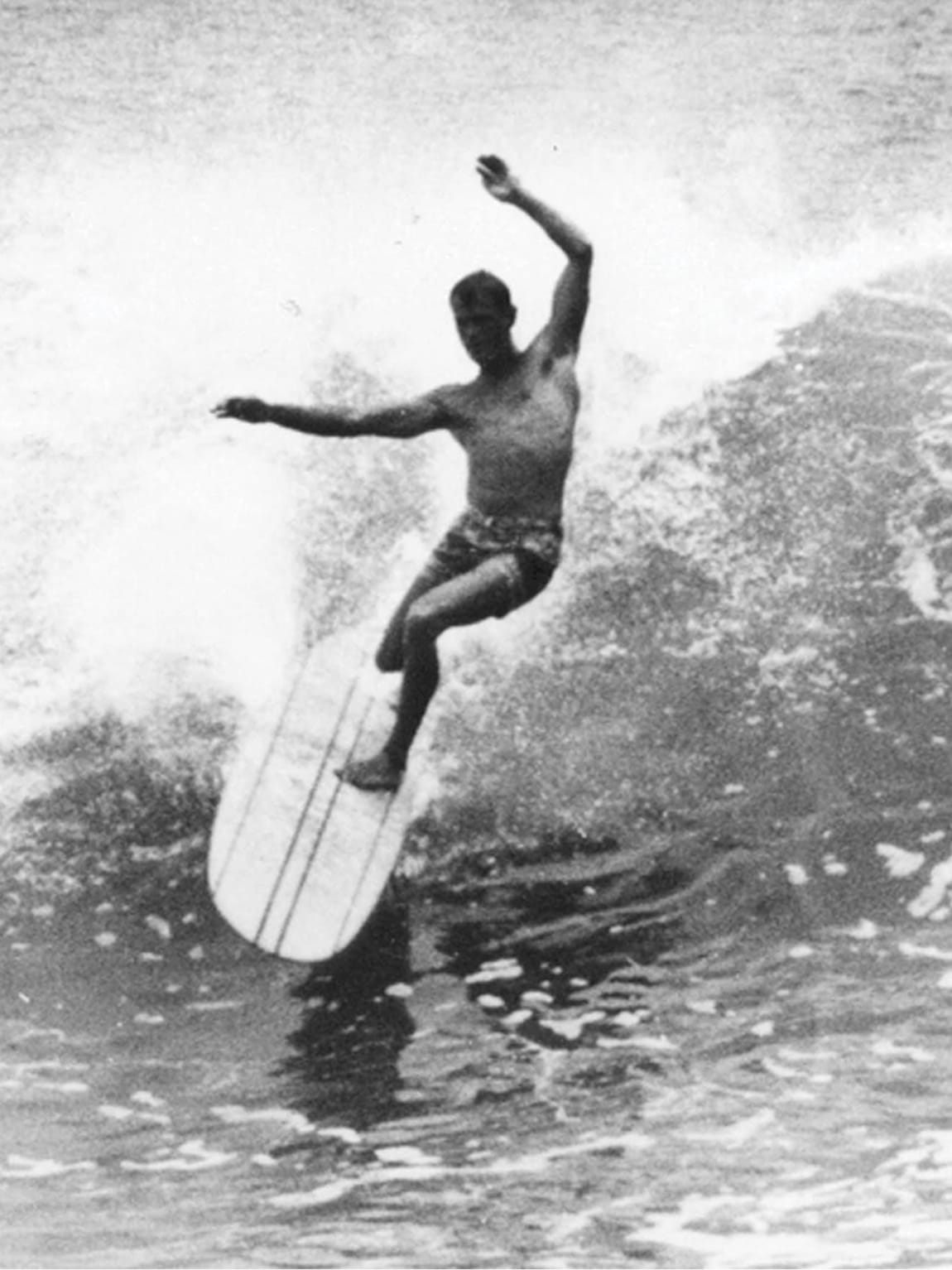 Historic black-and-white photograph of a surfer riding a wave off Dana Point