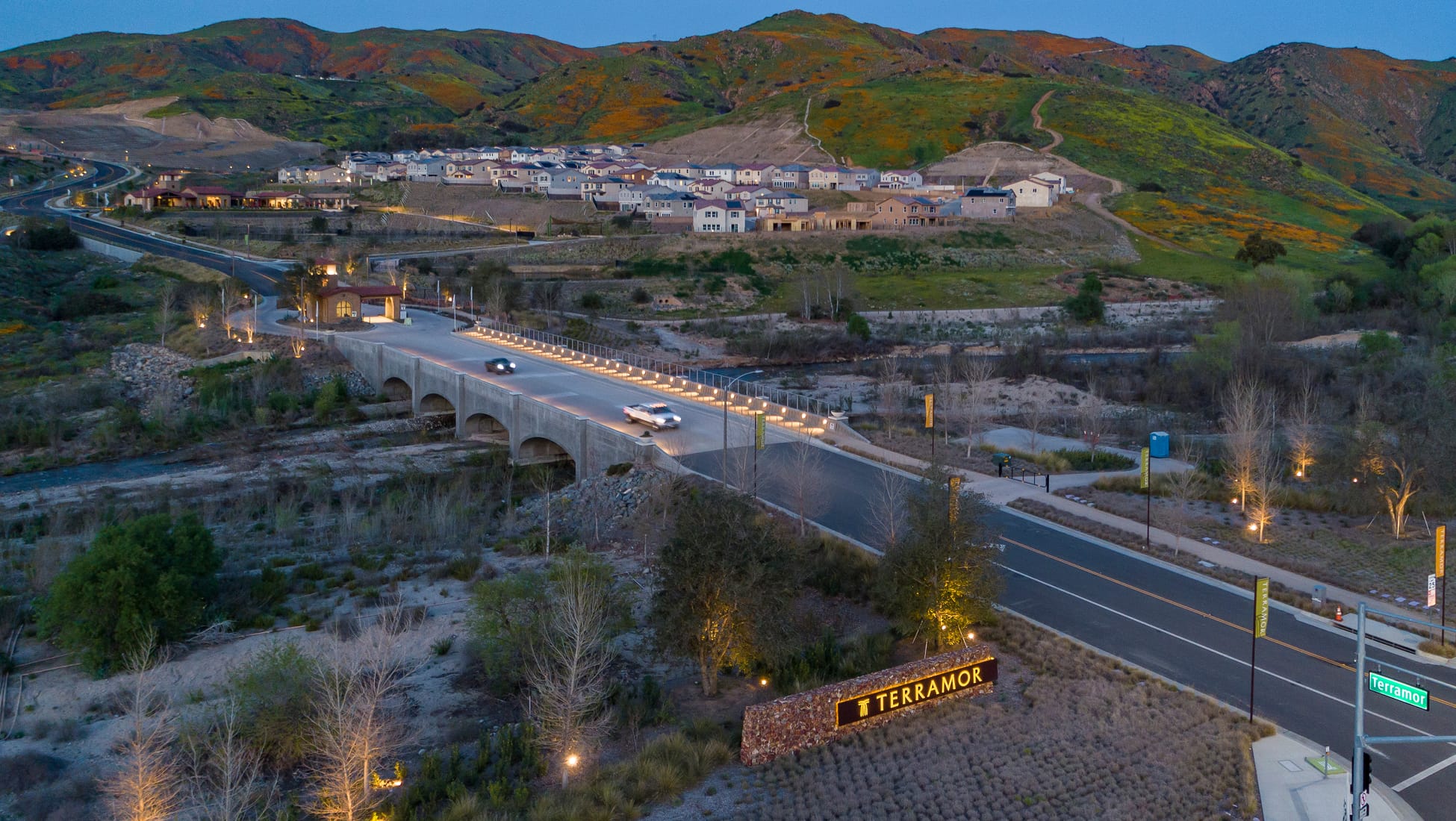 Aerial view at dusk of the illuminated bridge entry and "Terramor" monument sign leading into the hillside community - environmental graphic design by RSM Design