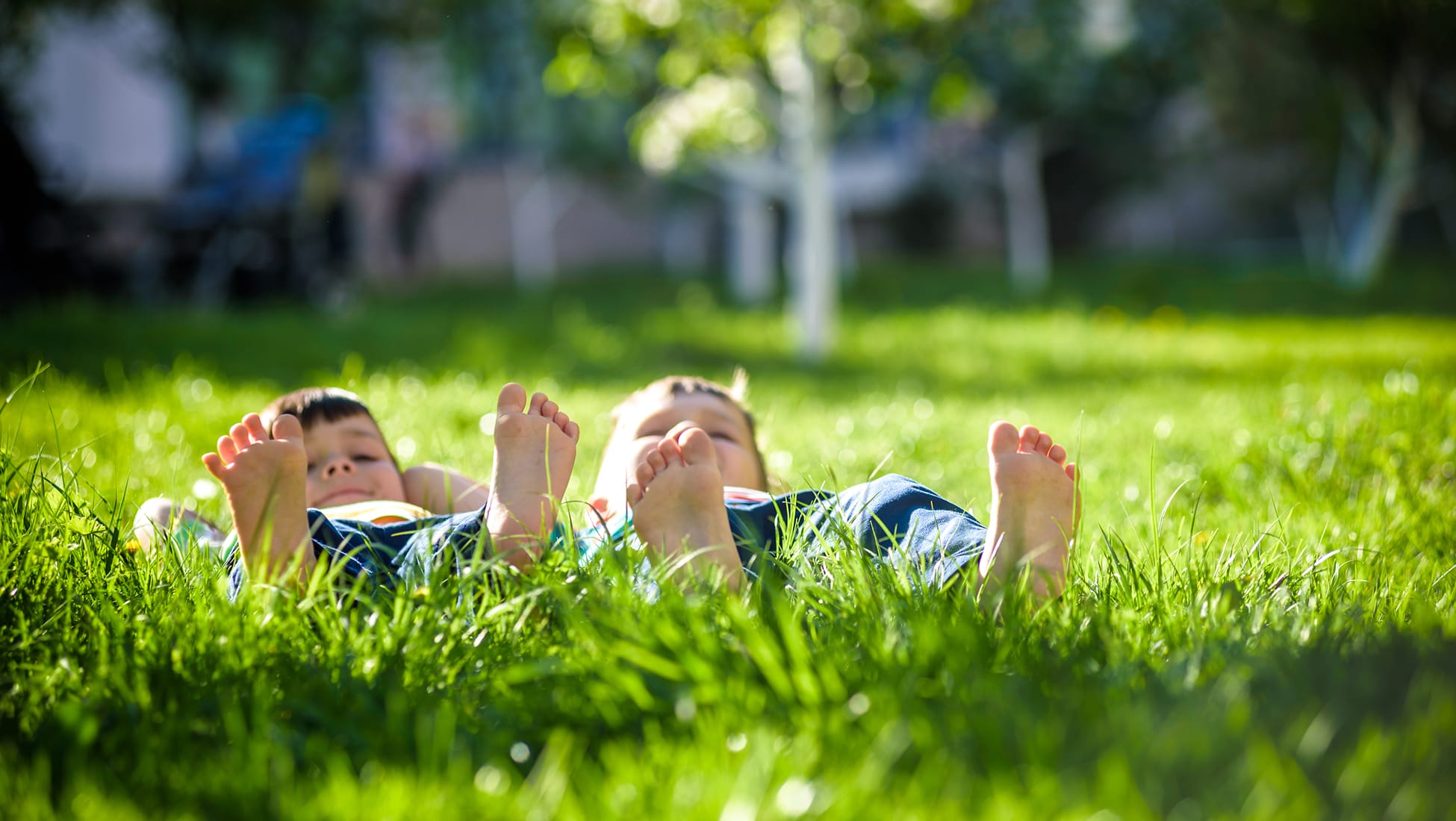 Children relaxing on grass in a sunny park at Whittier Village, highlighting family-friendly open space, greenery, and community-focused placemaking within a residential neighborhood.