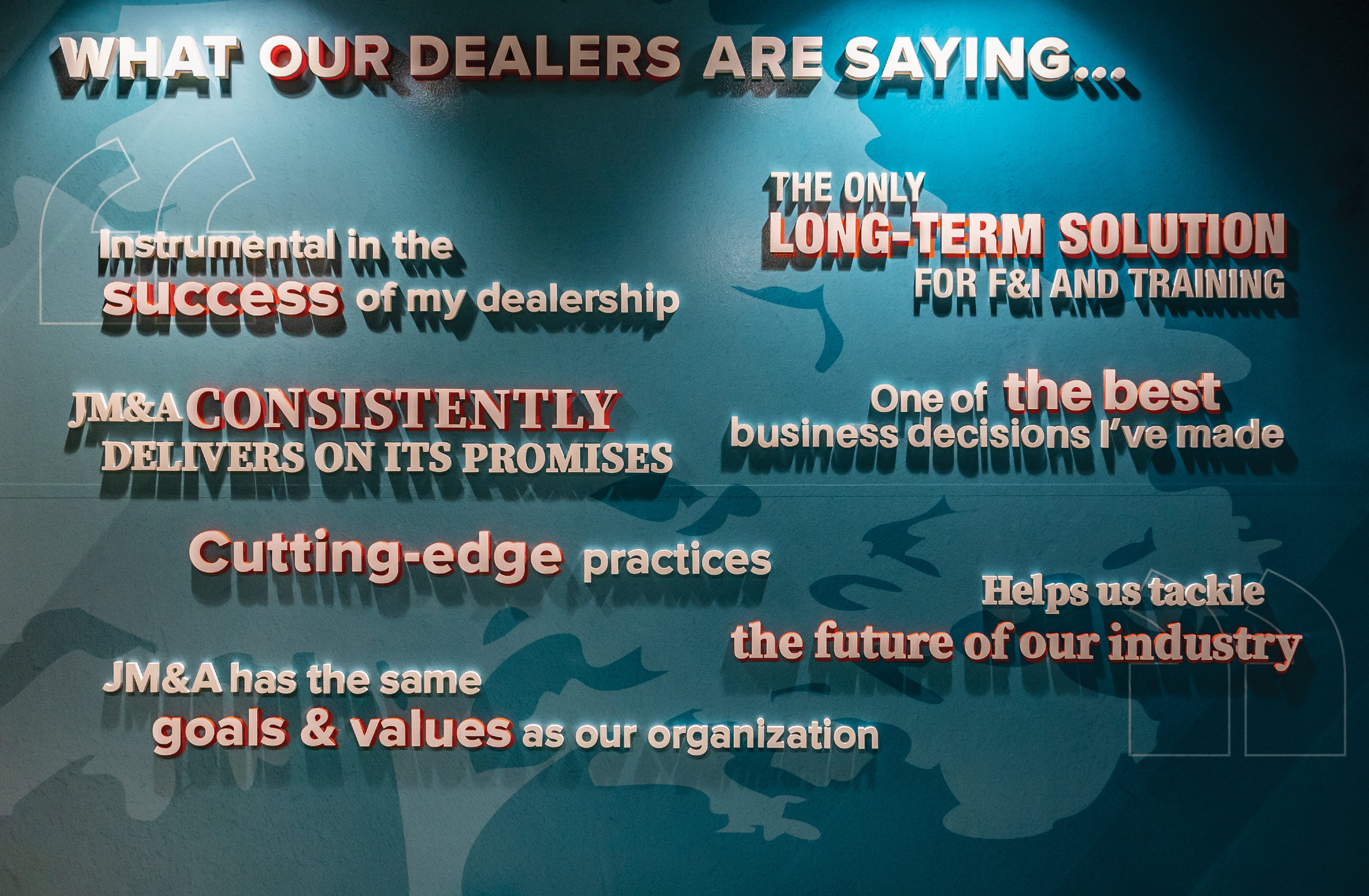Environmental graphic design feature wall with dimensional typography showcasing customer testimonials, integrating brand storytelling, experiential graphics, and interior branding within a corporate workplace, supporting placemaking, wayfinding, and branded user experience for the automotive industry.