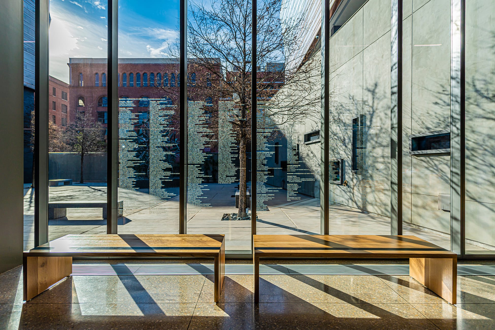 Donor recognition wall with sandblasted glass names overlooking courtyard at Dallas Holocaust and Human Rights Museum - donor recognition design by RSM Design