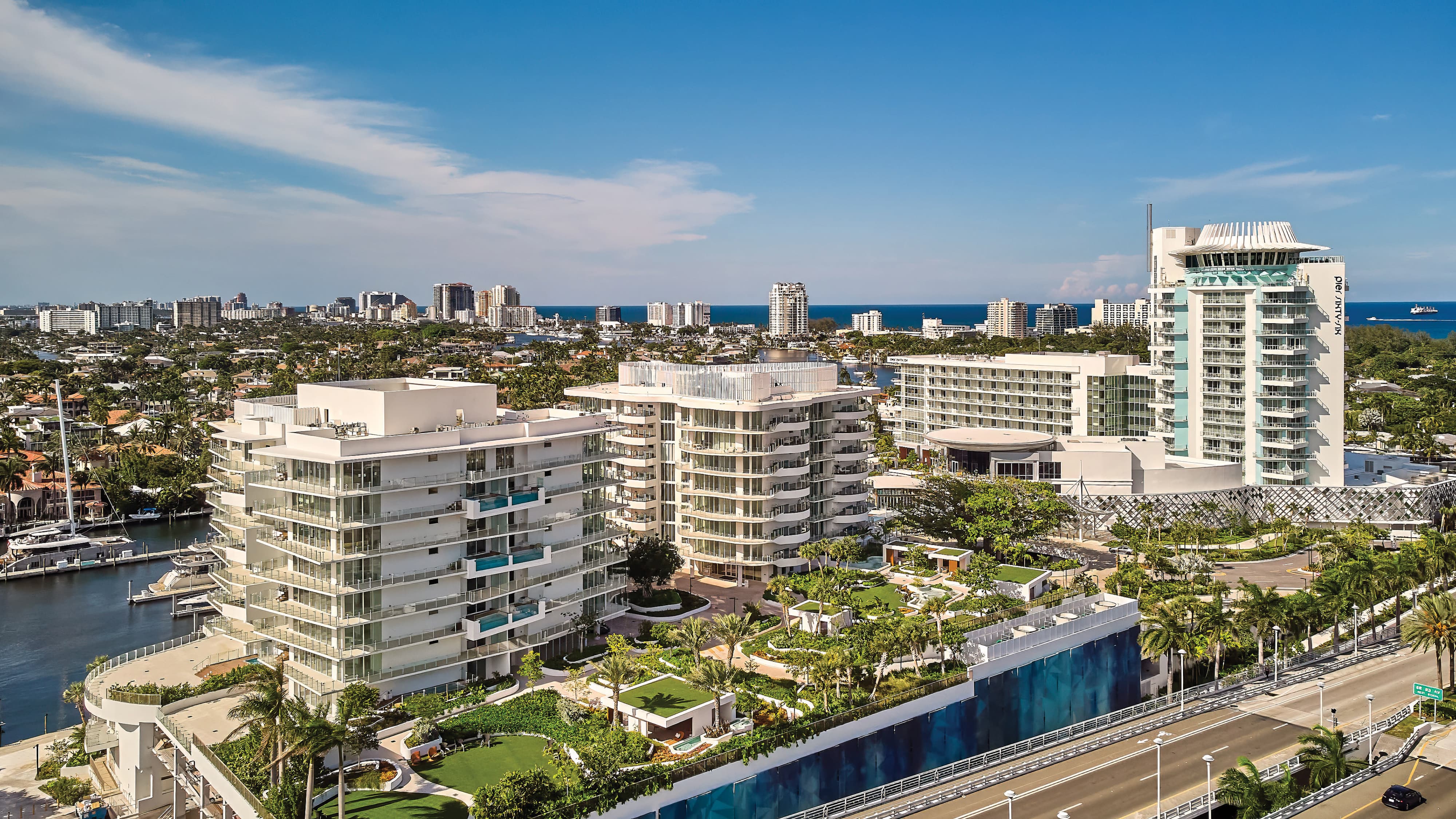 Aerial view of Pier Sixty-Six luxury waterfront resort and residential complex in Fort Lauderdale, Florida, featuring the iconic rotating tower, large-scale experiential graphic wall along the streetscape, marina-facing towers, and lushly landscaped grounds — RSM Design environmental graphic design, experiential placemaking, branded environments, and wayfinding and signage design for hospitality, waterfront, and residential community destinations.