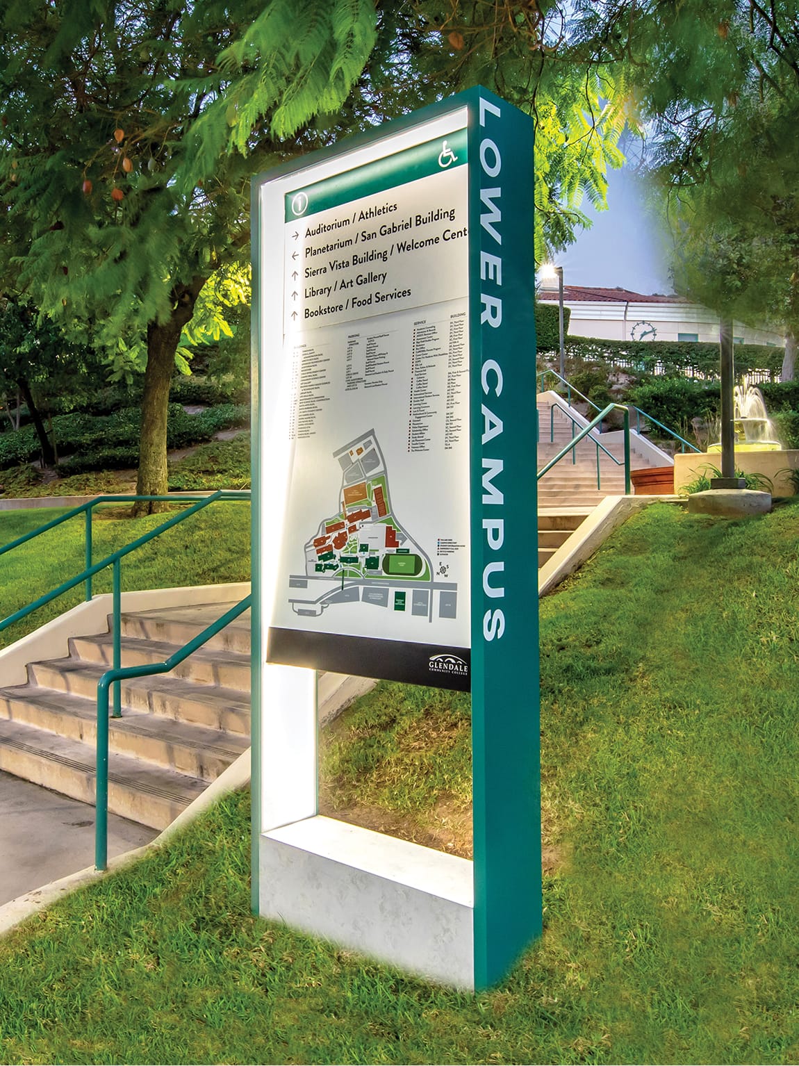 Illuminated Lower Campus directory pylon at Glendale Community College designed by RSM Design, featuring a teal branded frame, campus map, and directional listings set among landscaped grounds at dusk