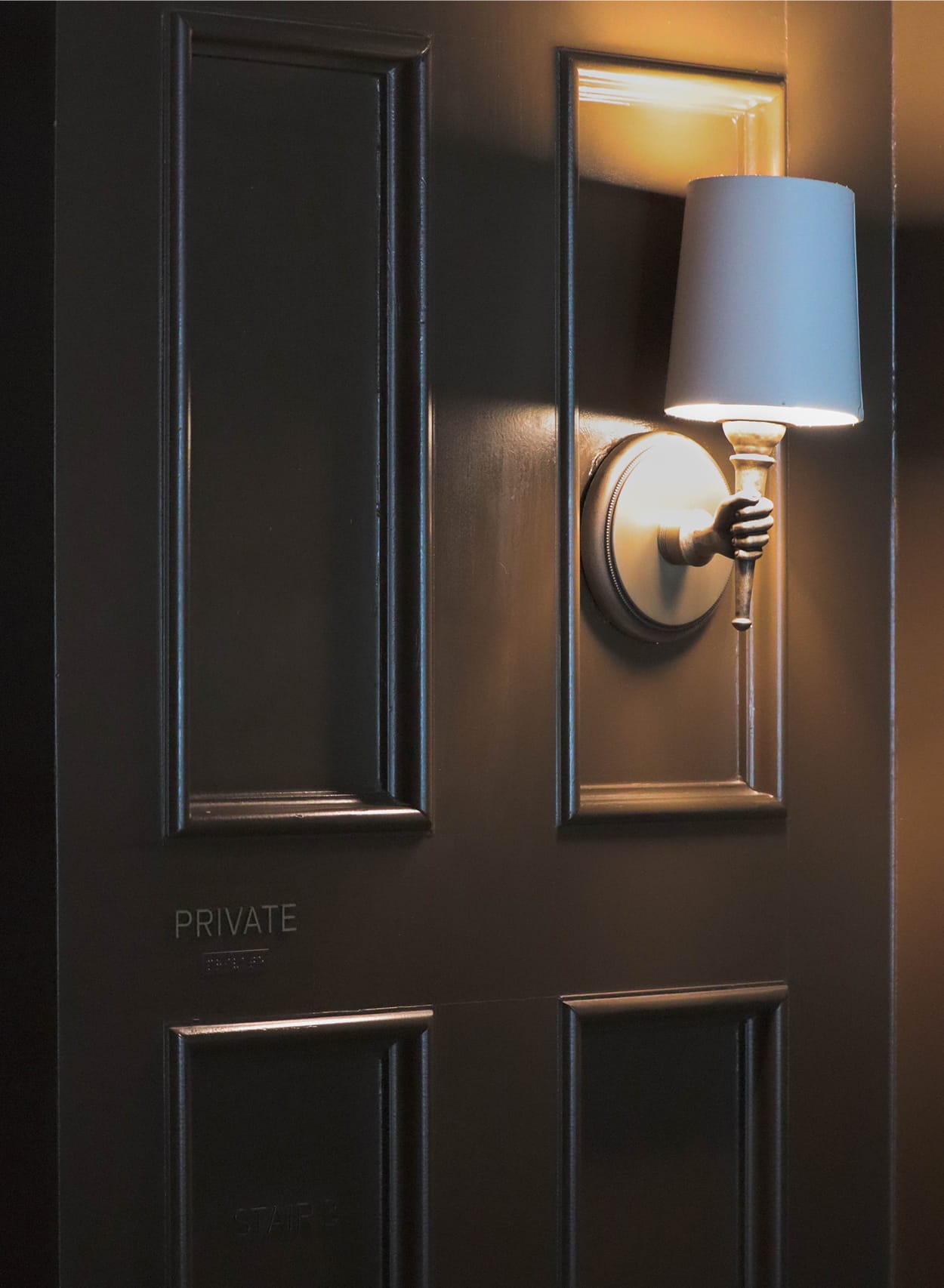 Understated "Private" door sign beside a sconce light fixture at The Swexan Hotel - environmental graphic design by RSM Design