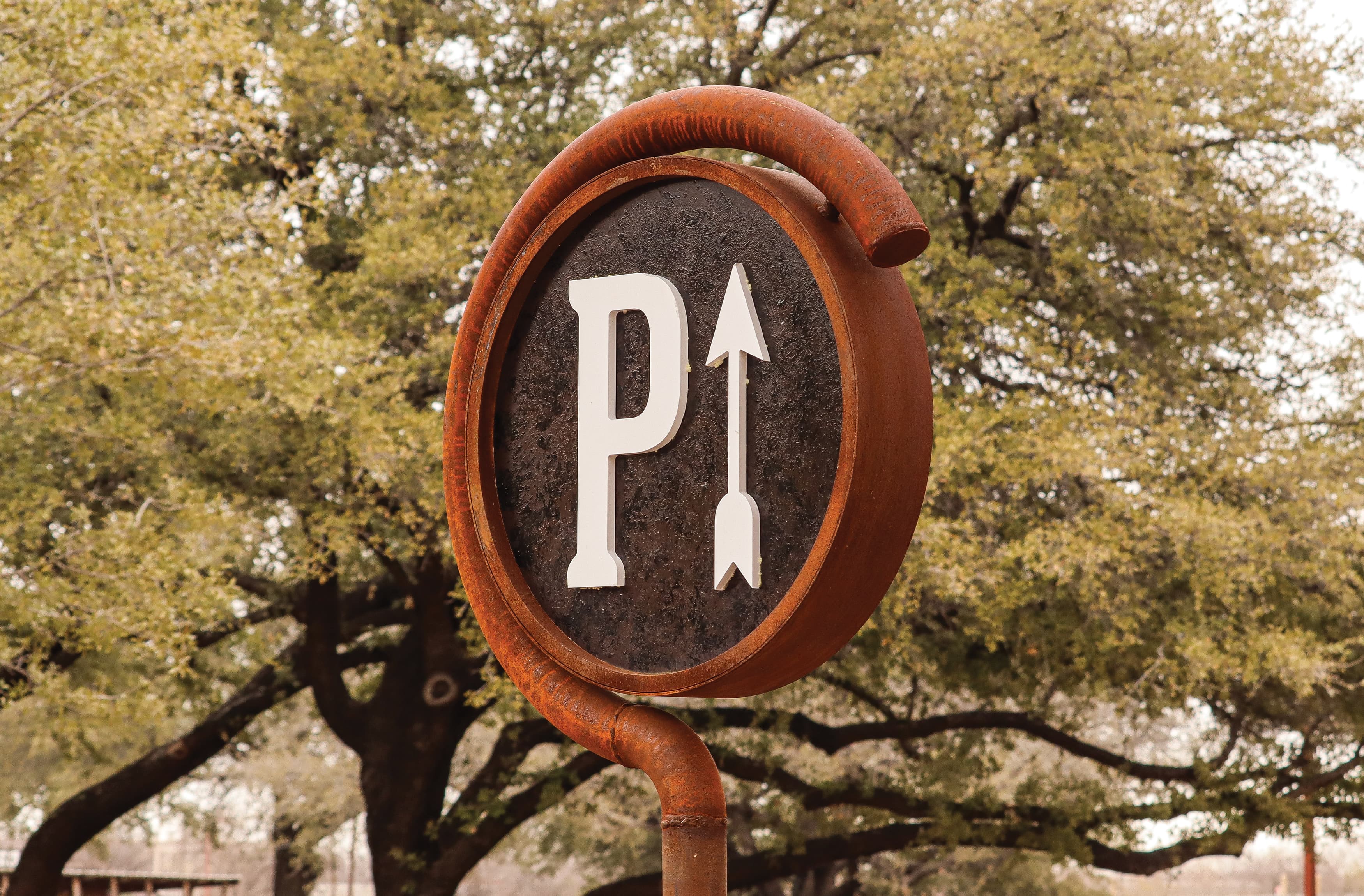Detail shot of circular parking directional sign. Parking "P" with an arrow. Rustic style sign. 
